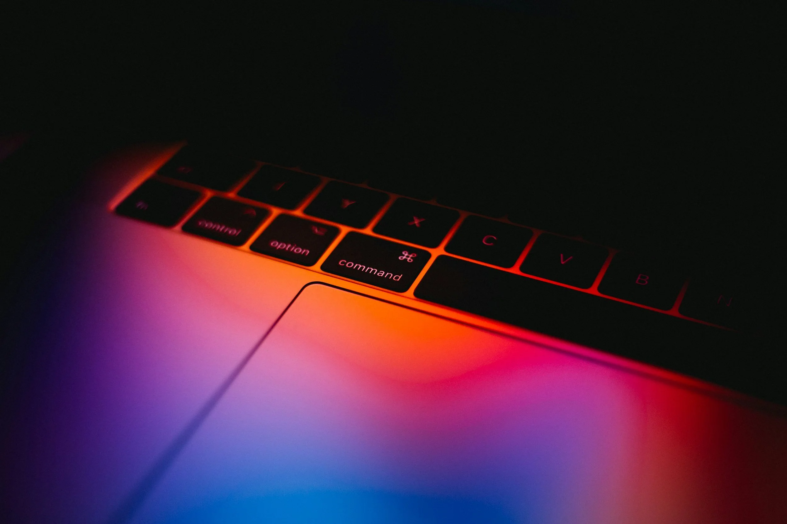 A close-up of a computer keyboard illuminated by vibrant neon lighting, representing digital copy and technical writing for Hype & Dexter.