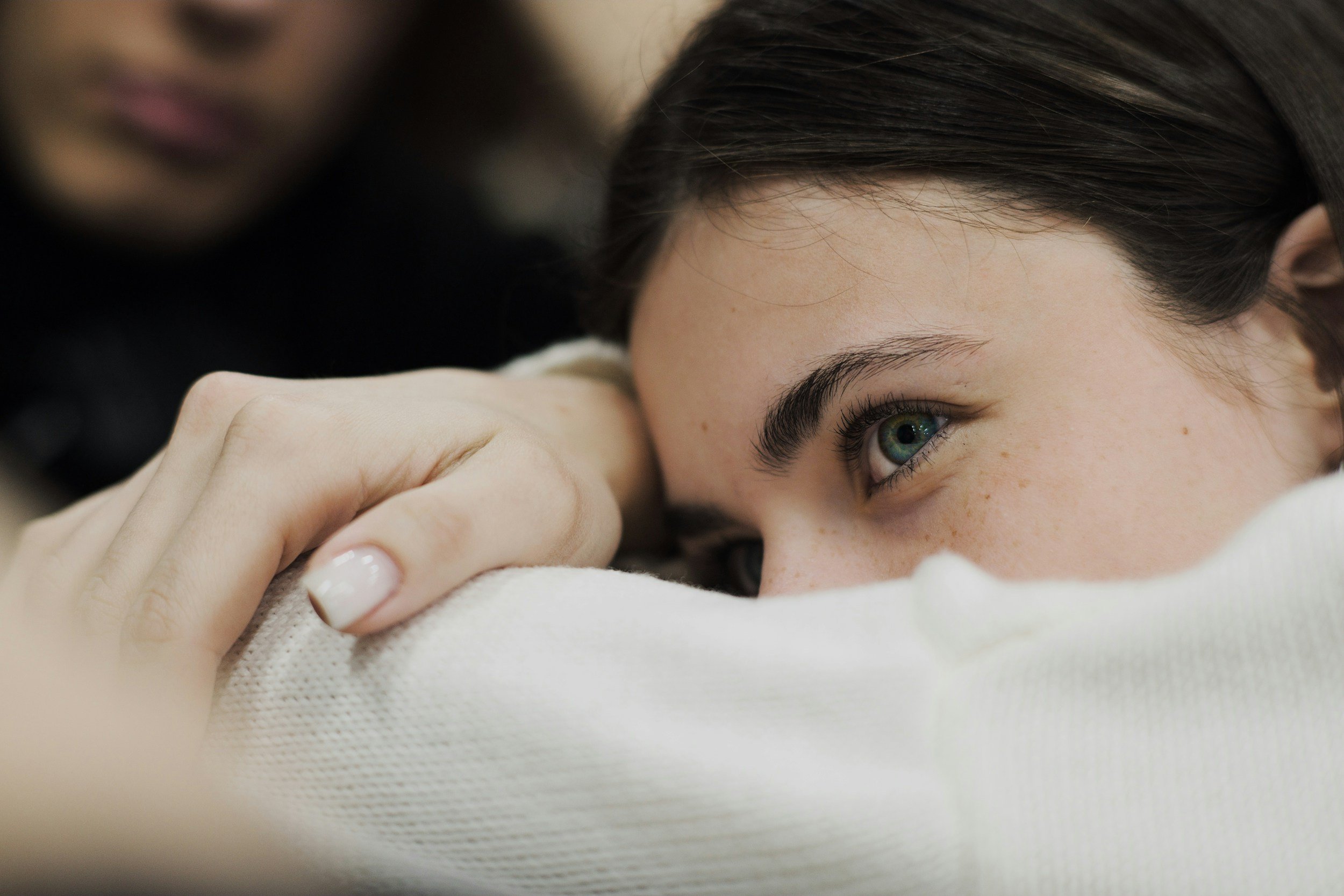 A thoughtful woman resting her head on her forearm, capturing the introspective and vulnerable tone of Danielle Ramaekers' literary fiction story 'One Day You’ll Be Grateful' in Please See Me Journal.
