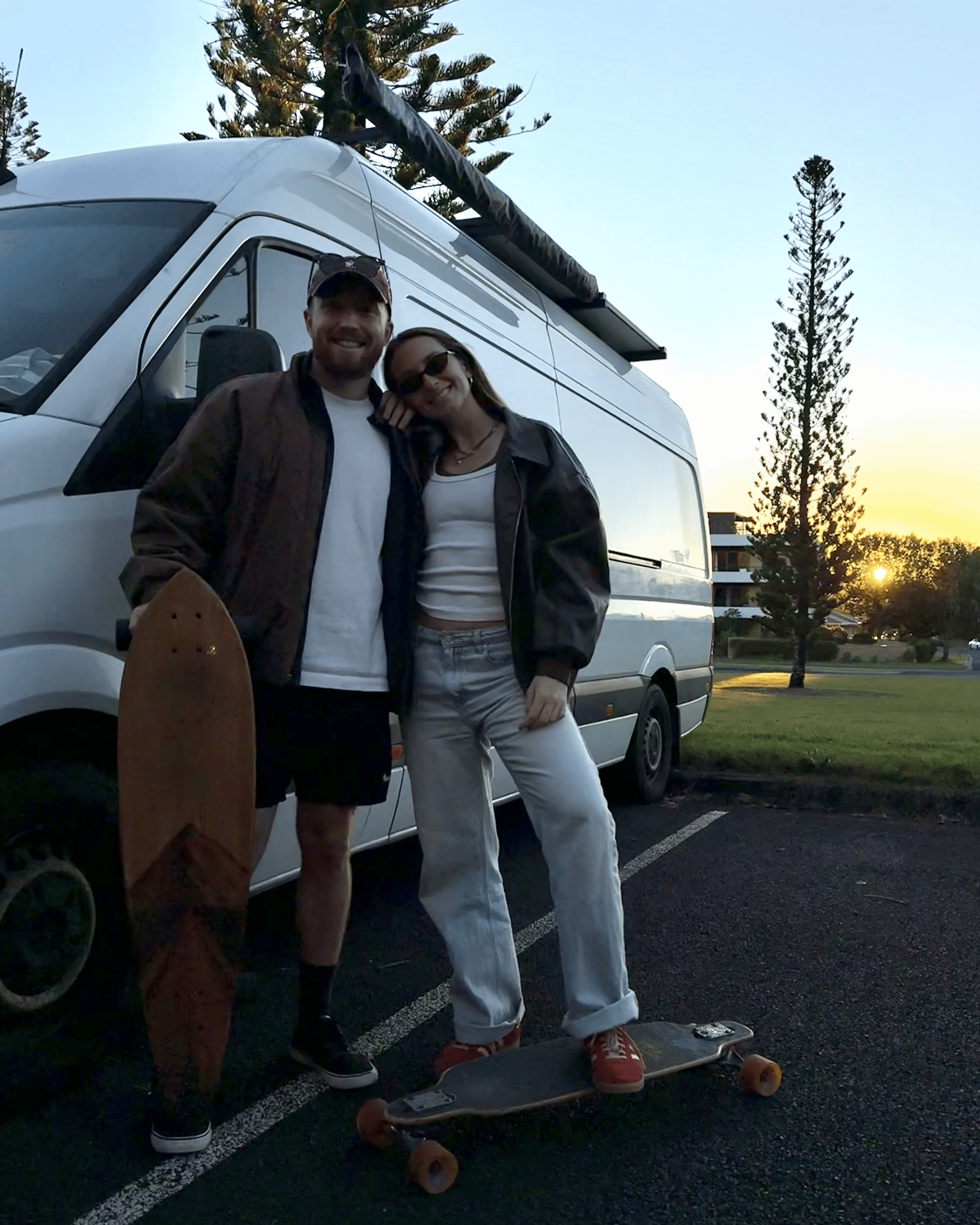 Morgan and Stu riding skateboards at sunset while living in a van.