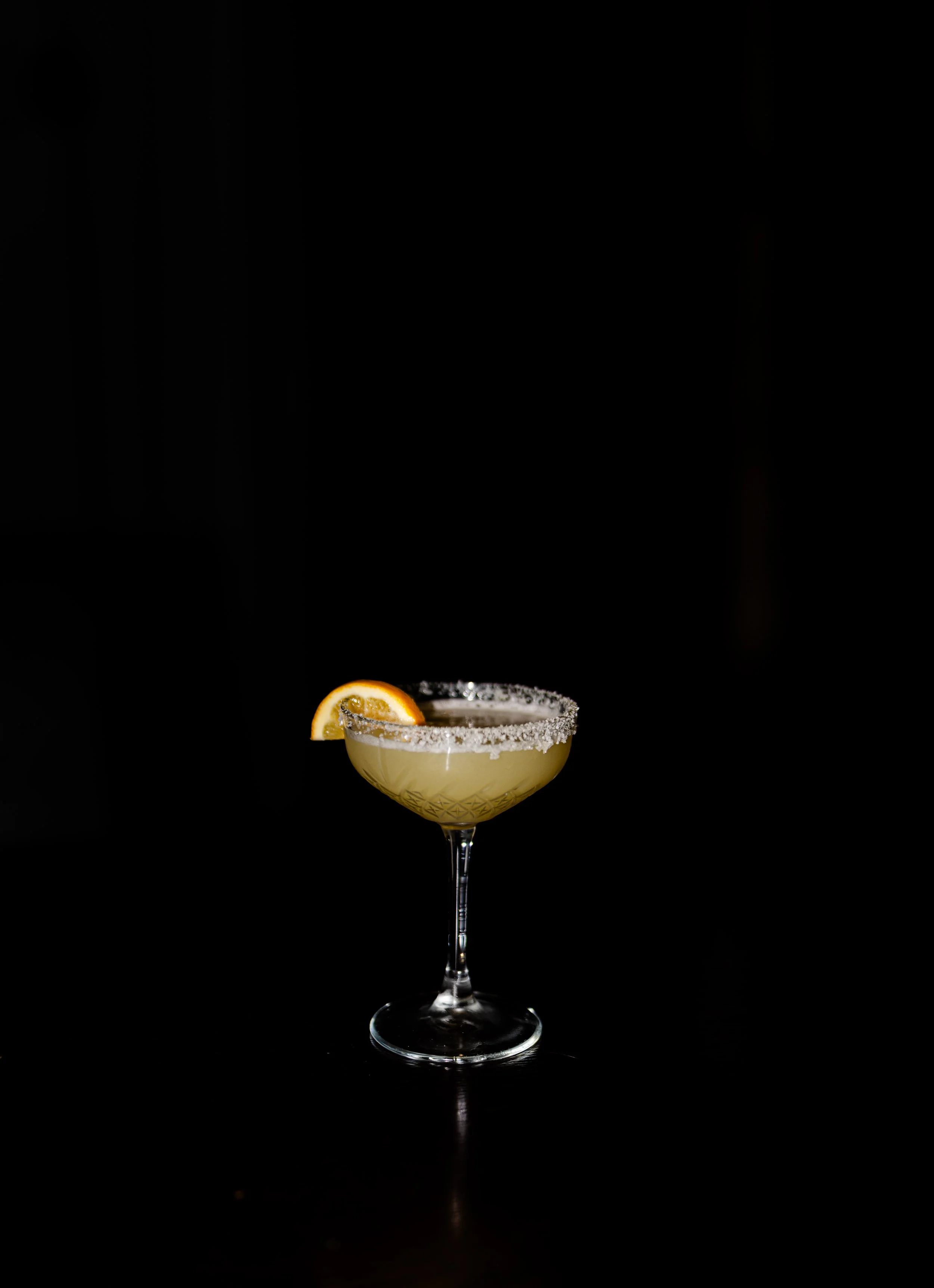 A cocktail in a martini glass garnished with a lemon slice and a salted rim, set against a romantic scene in Christchurch