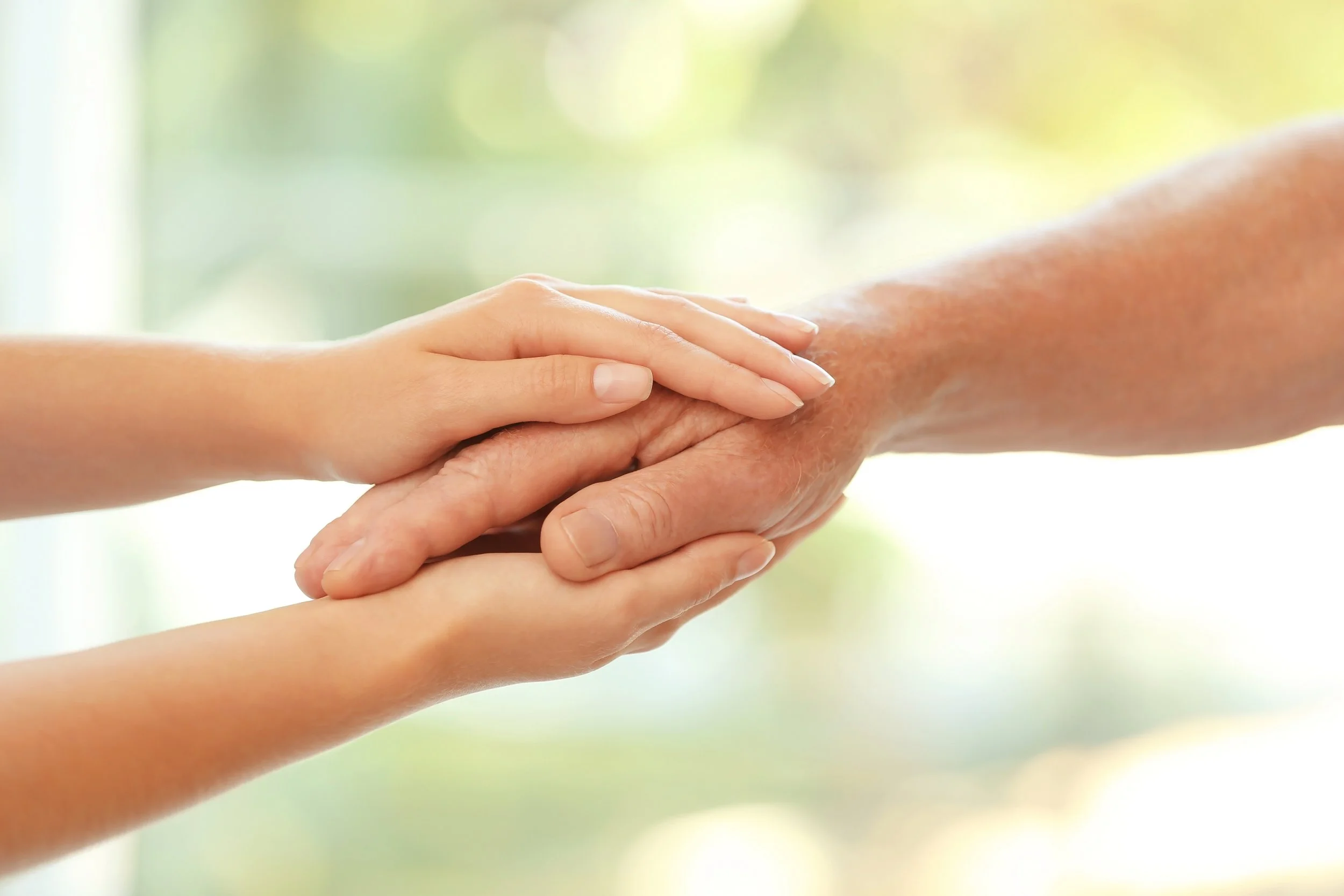 Two hands, one younger and one older, holding each other.