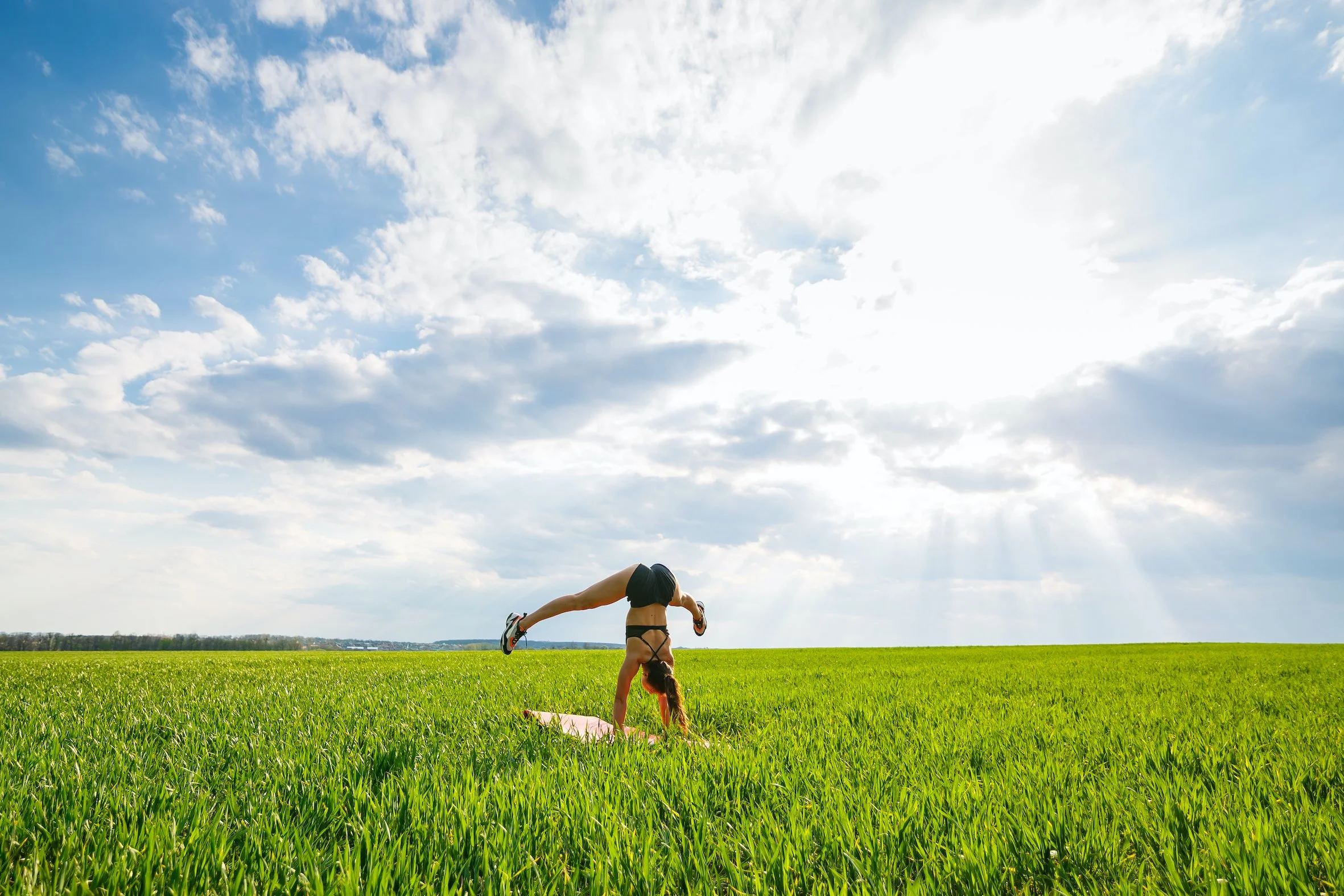 a women full of dynamic vitality doing a handstand in a field