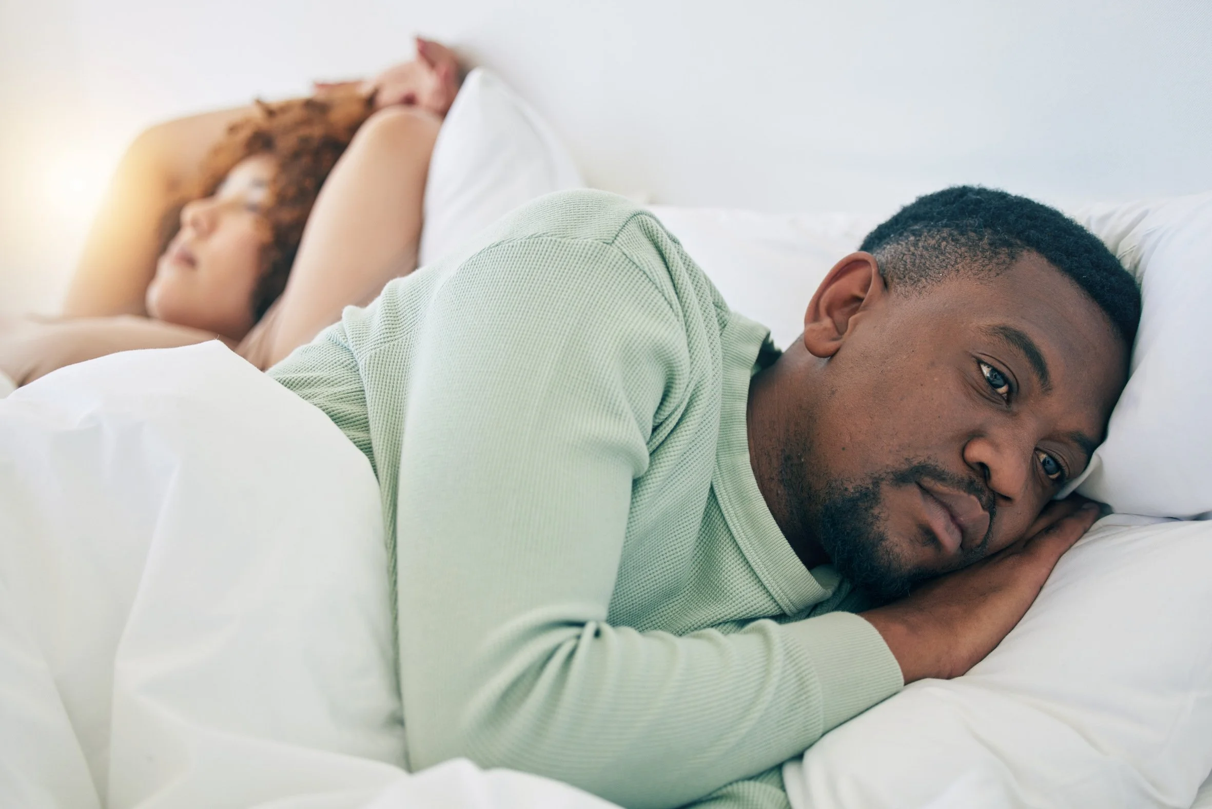 man who has slept lightly and awake next to deep sleeping partner