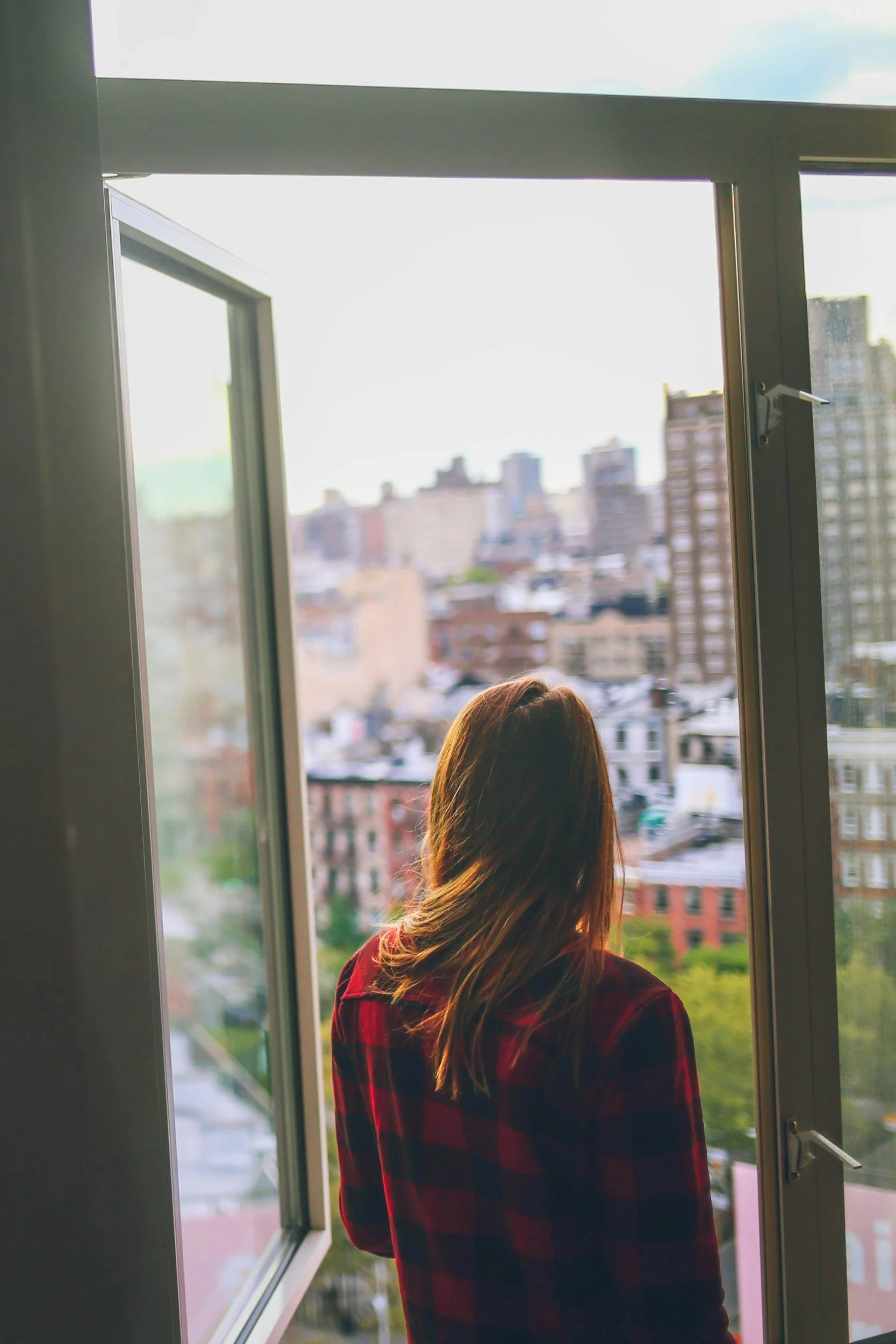 woman looking out her window after anxiety therapy nyc