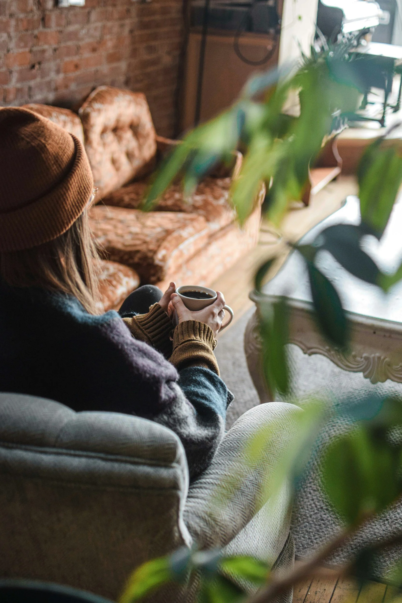 woman sitting on a couch with plants after healing from ifs therapy nyc