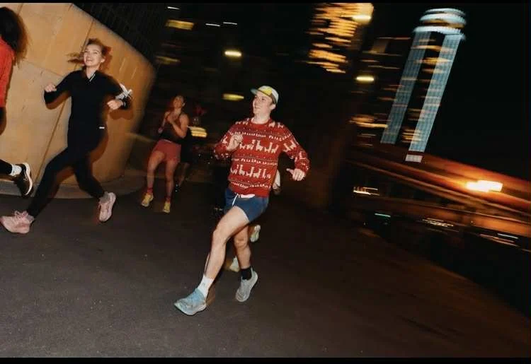 Young people running at night in an urban setting, with city lights and buildings in the background.