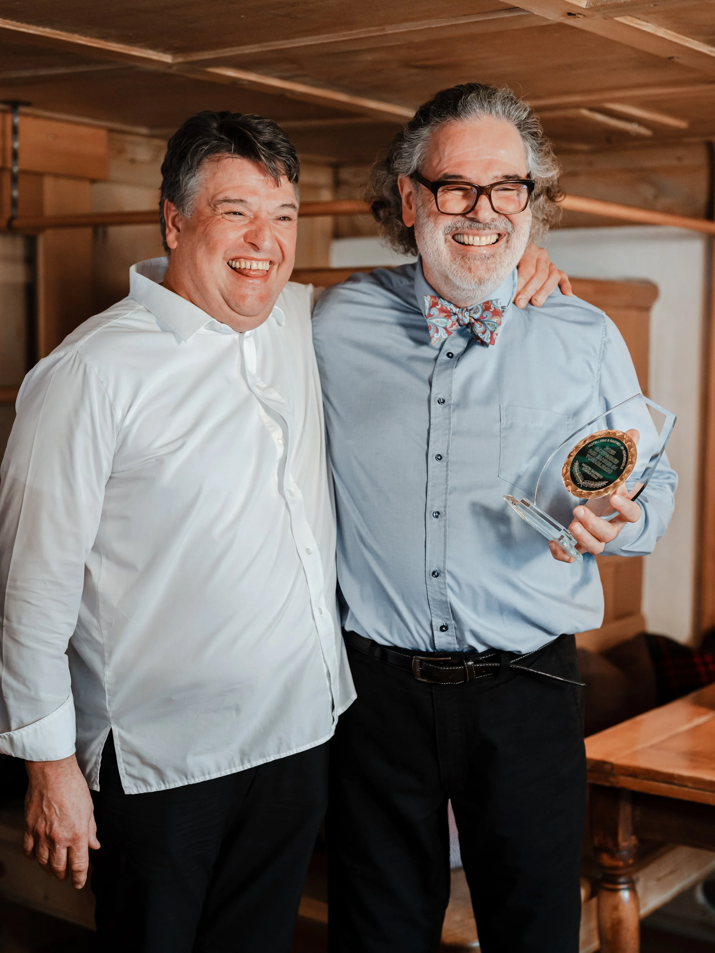 Ein Mann und eine Frau stehen vor einem Holzhaus, lachen und unterhalten sich.