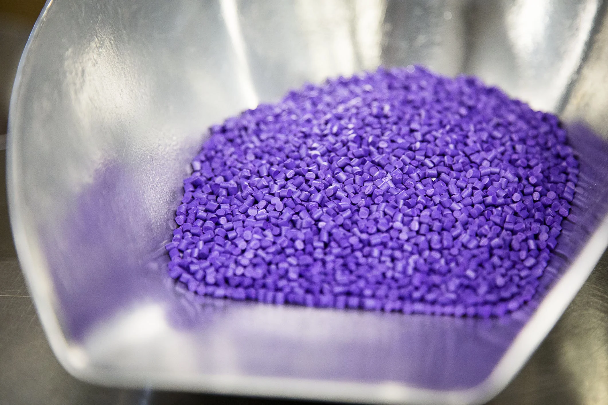 Violette kleine Kunststoffpellets in einem metallischen Behälter