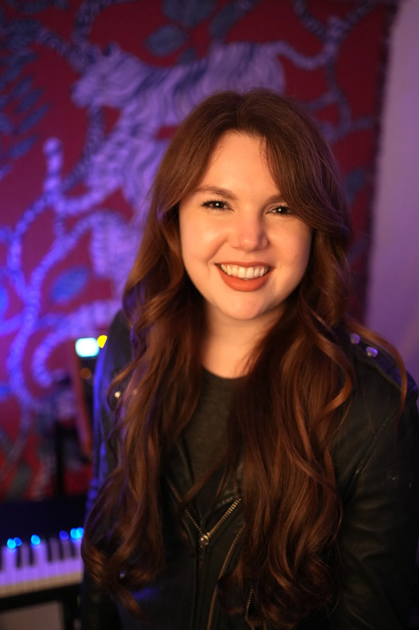 Claire Donzelli, founder of Clarity Music Marketing and music publicist, smiling in a professional headshot with warm studio lighting and a purple music studio background.