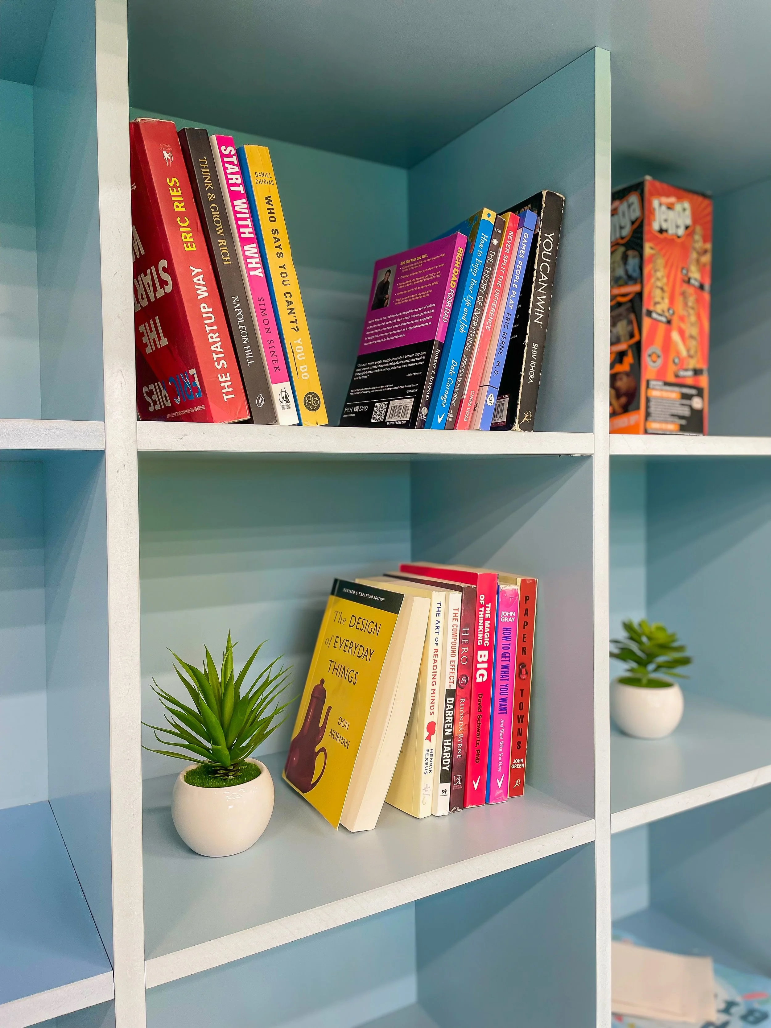 A blue bookshelf with books and small potted plants.