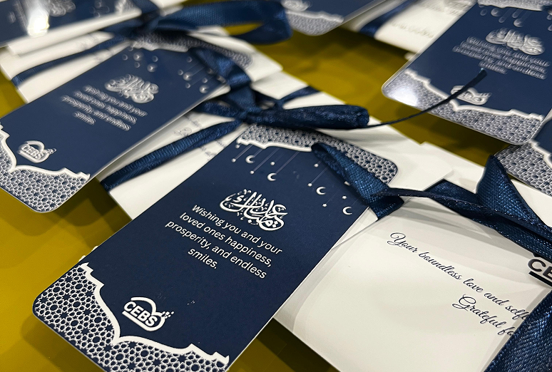 Close-up of navy blue and white event tags with luxurious design, attached to blue silk ribbons, with a message wishing happiness and prosperity for loved ones.