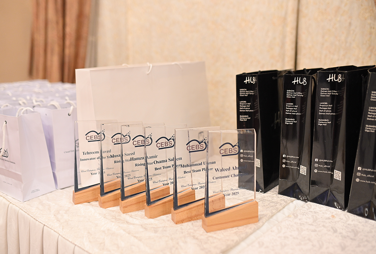 Several glass awards with wooden bases and black gift bags on a table.