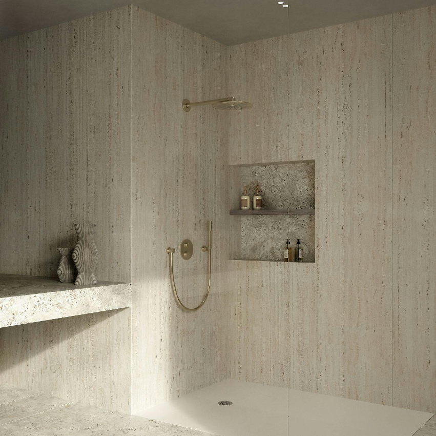 Salle de bain minimaliste avec un espace douche, étagère intégrée en pierre, accessoires de douche en bronze, et deux vases en céramique sur une surface en pierre.