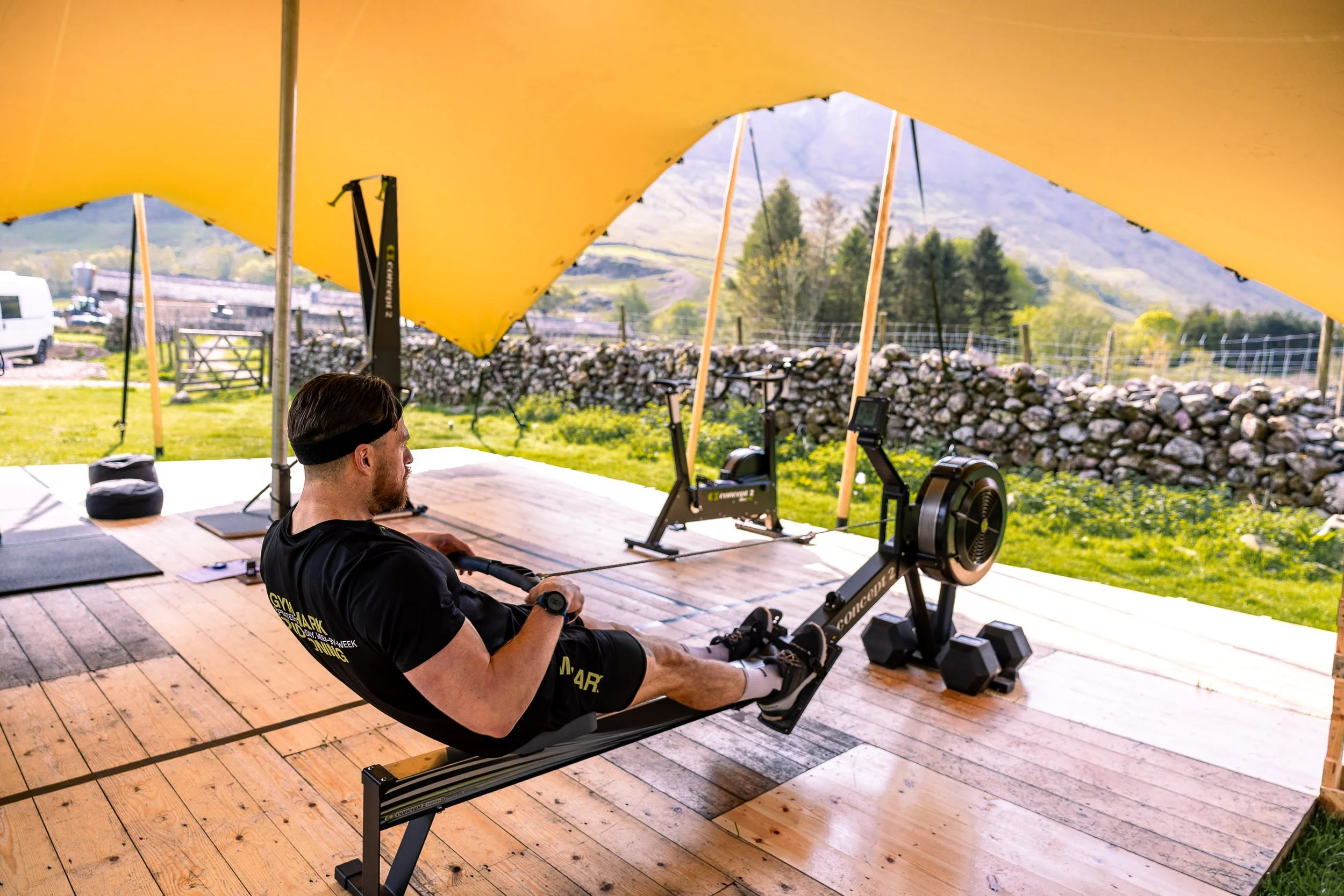 Woman working out on rowing machine at gym, with other people in the background.