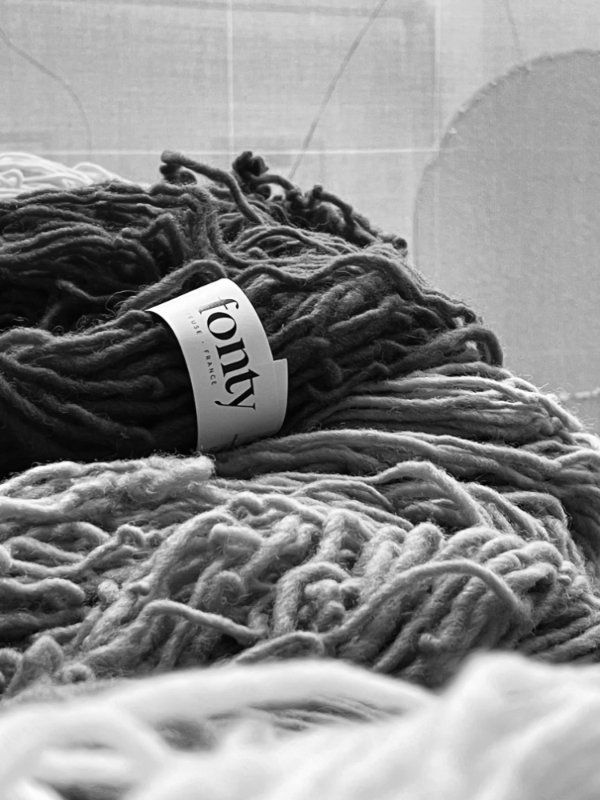 Close-up view of a pile of yarn or thick thread, with a visible label that reads 'Fony' or 'Fony' in black font, in a black and white photograph.