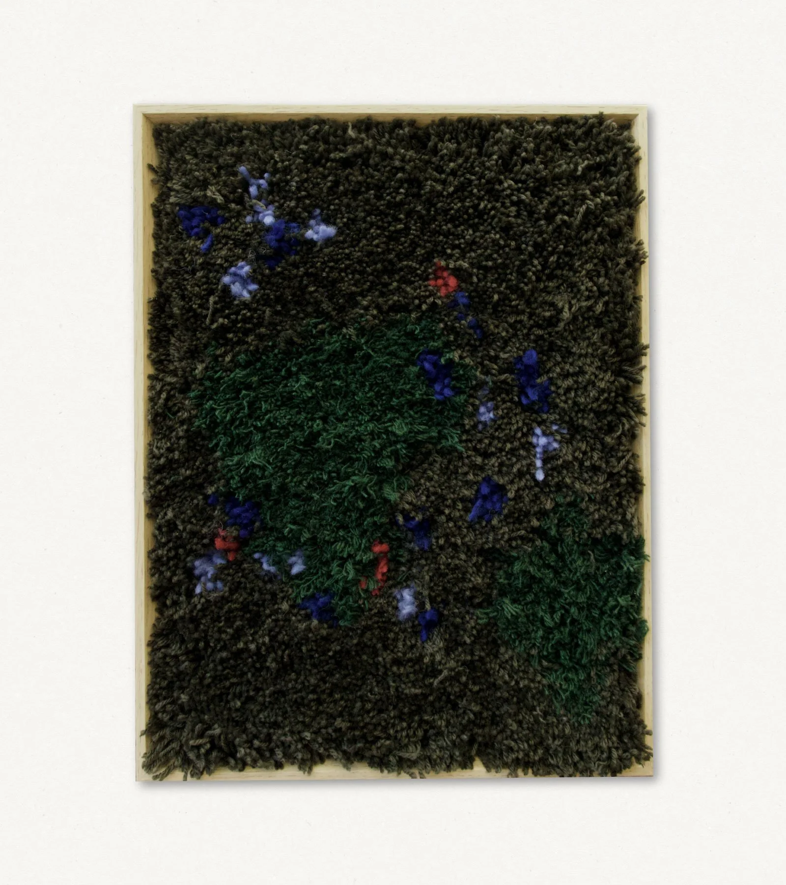 Textural mixed media art piece with dark brown, green, and colorful fabric elements framed in light wood.
