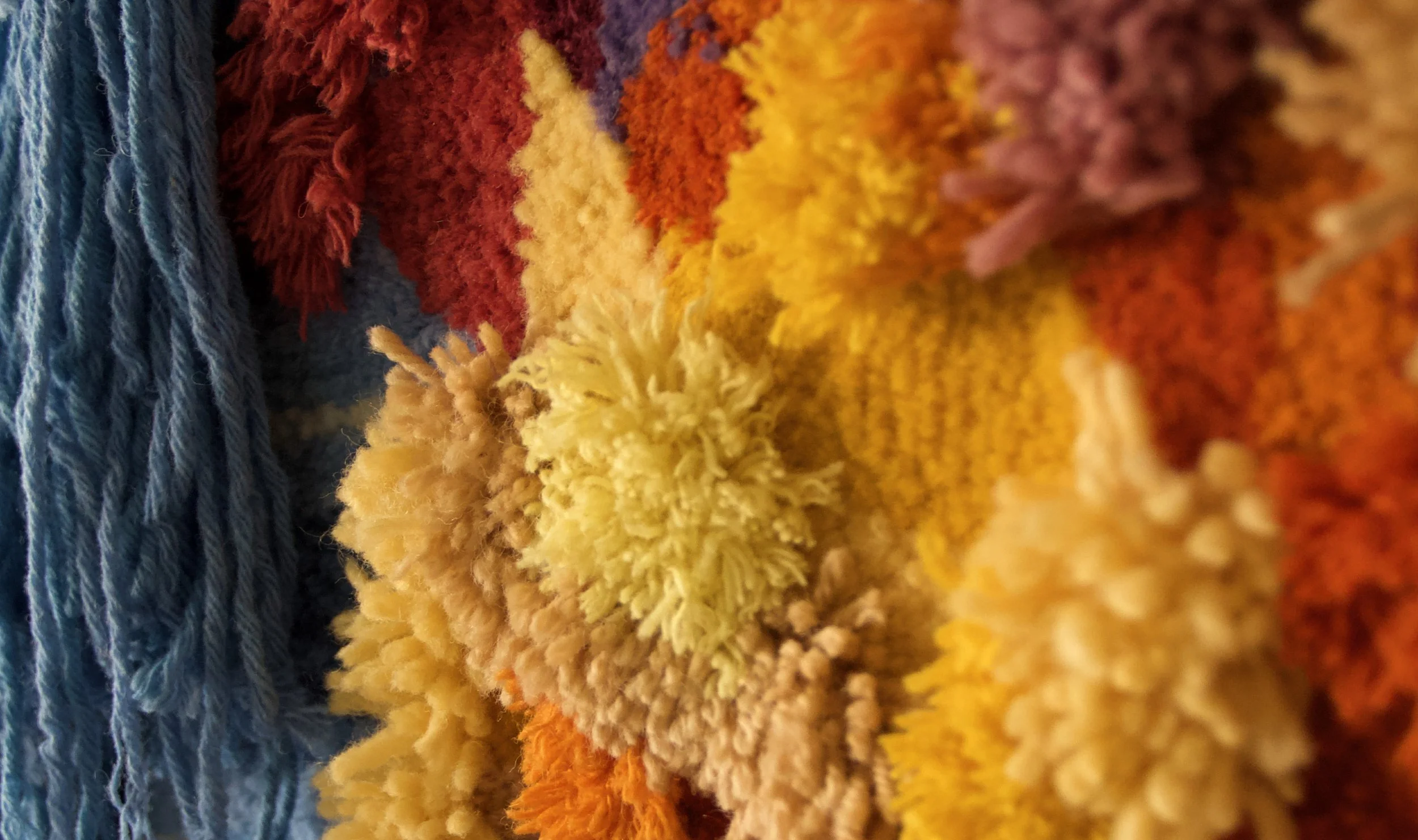 Close-up of a multicolored, textured yarn or woven fabric with colors including blue, red, yellow, and orange.
