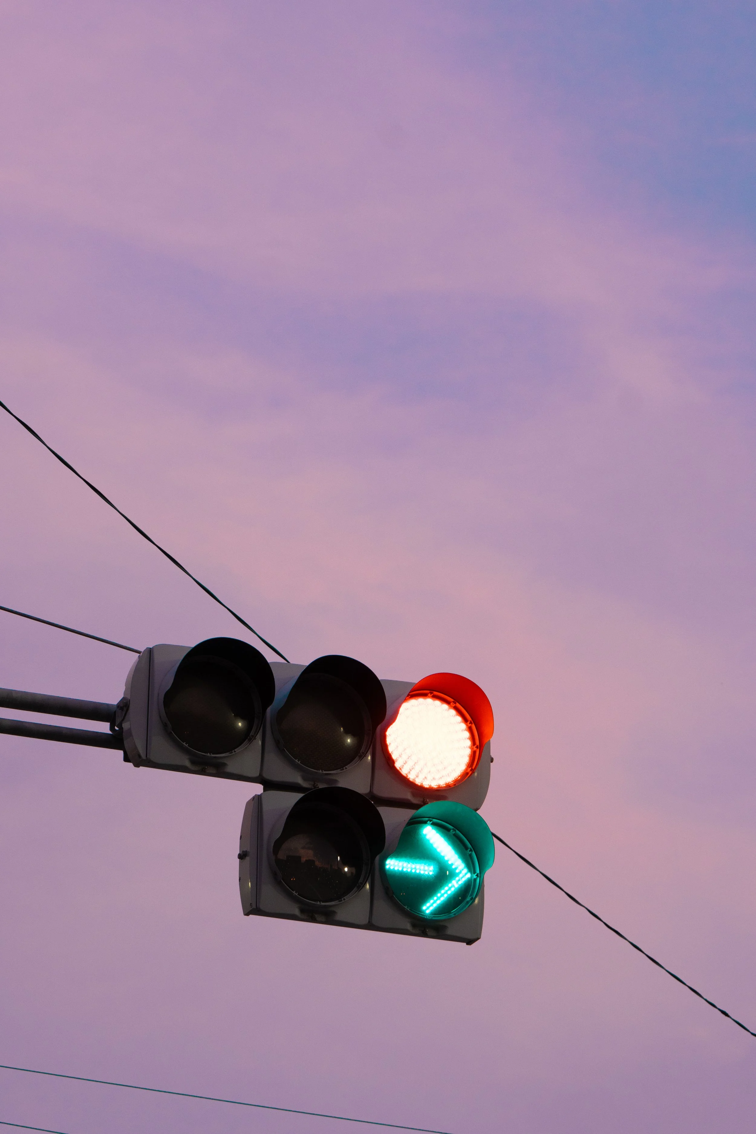 Traffic light showing red and green signals with a purple sky in the background.