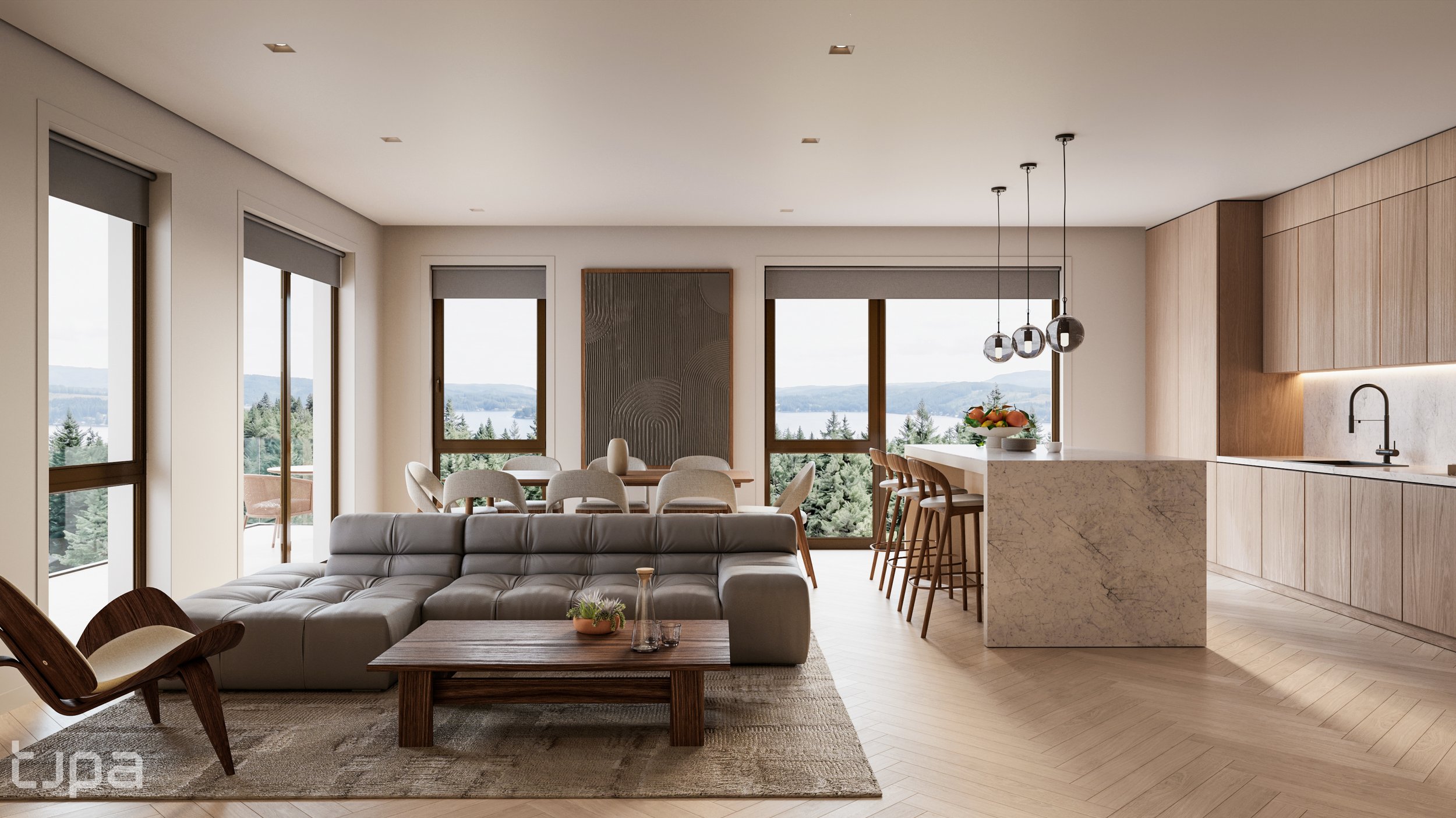 Modern open-plan living room and kitchen with large windows showing a scenic view of trees and mountains, neutral-colored furniture, a dining table, bar stools, and a kitchen island with a bowl of fruit.