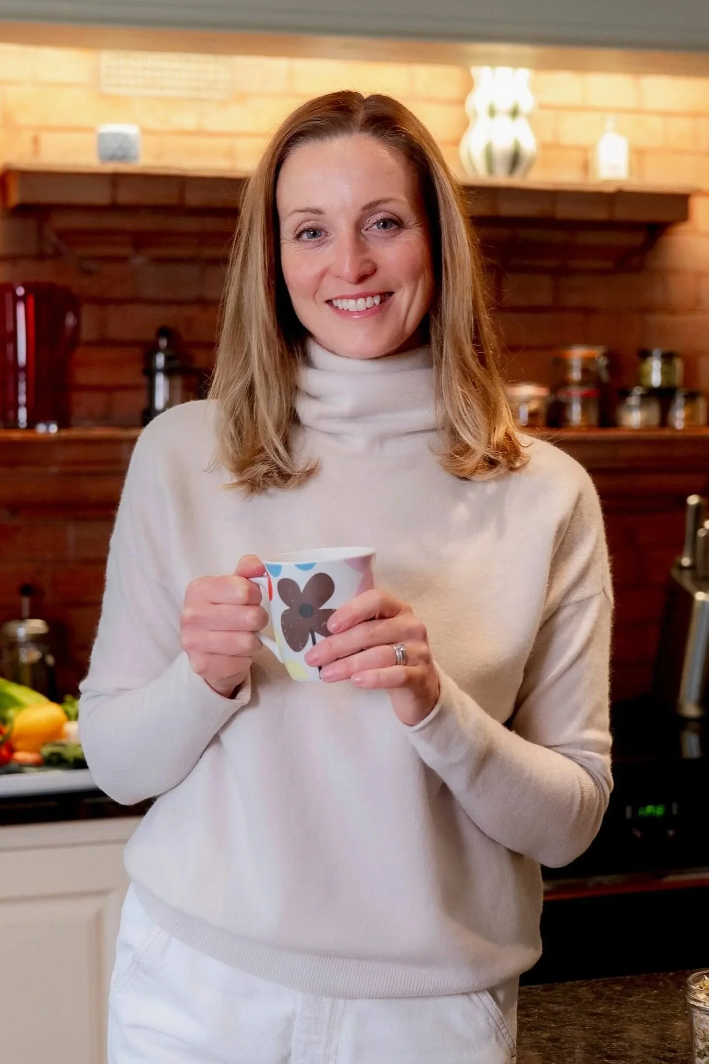 Niamh Ward, Registered Nutritionist and Health Coach, holding a cup of tea in her kitchen