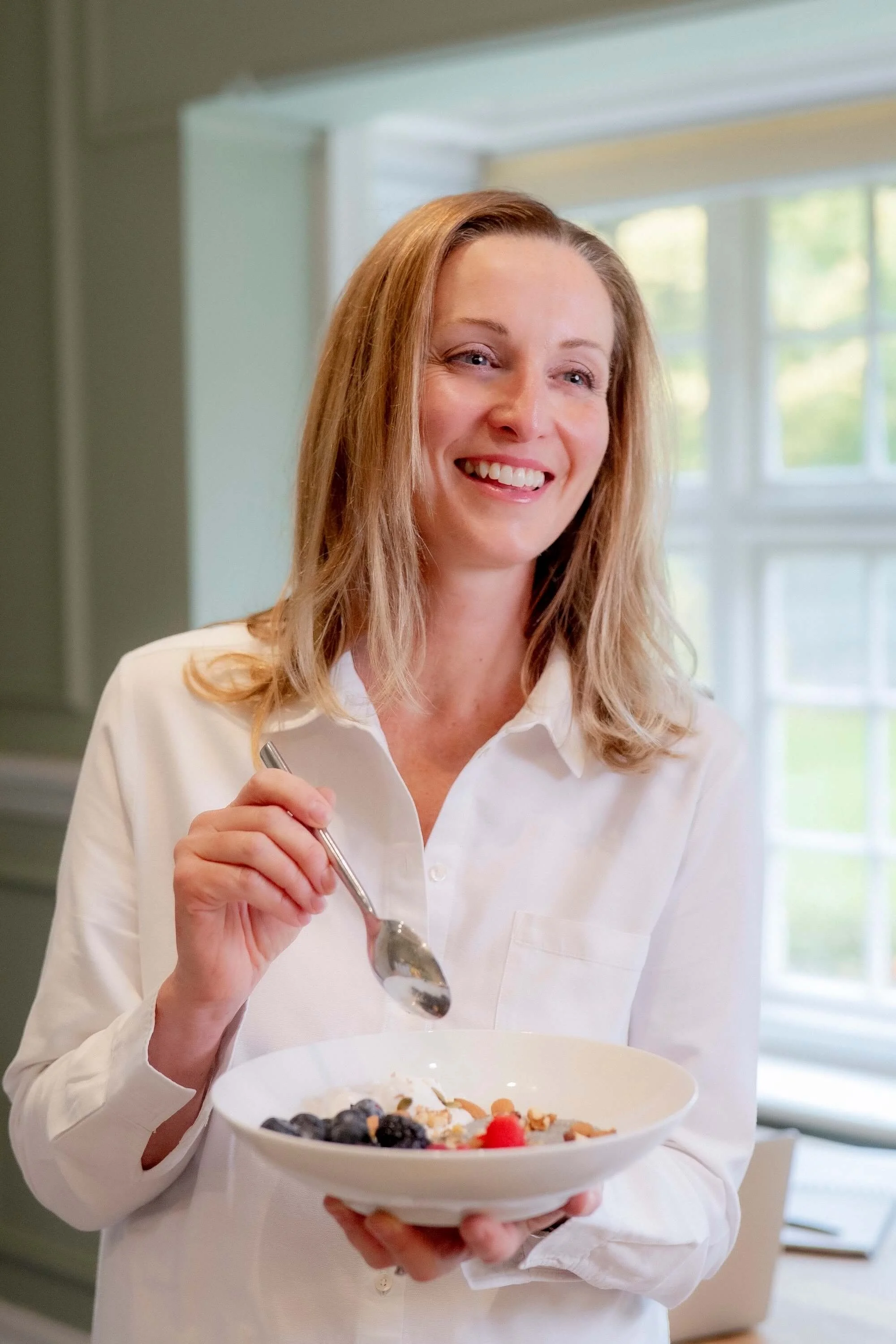 Niamh Ward, Registered Nutritionist and Health Coach, holding a breakfast bowl and laughing