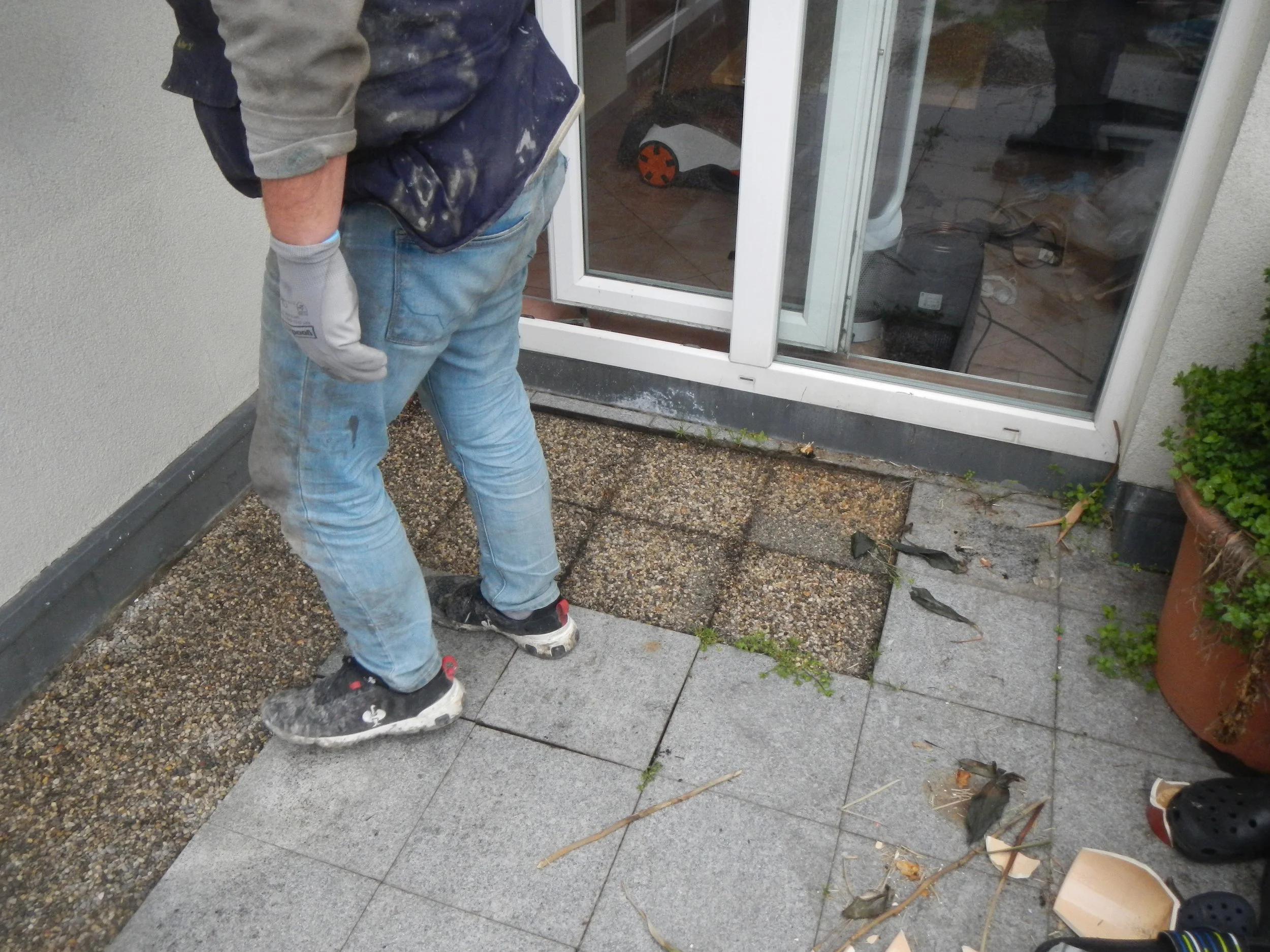 Arbeiter begutachtet die schadhafte und undichte Anschlussstelle zwischen Terrassentüre und Terrasse