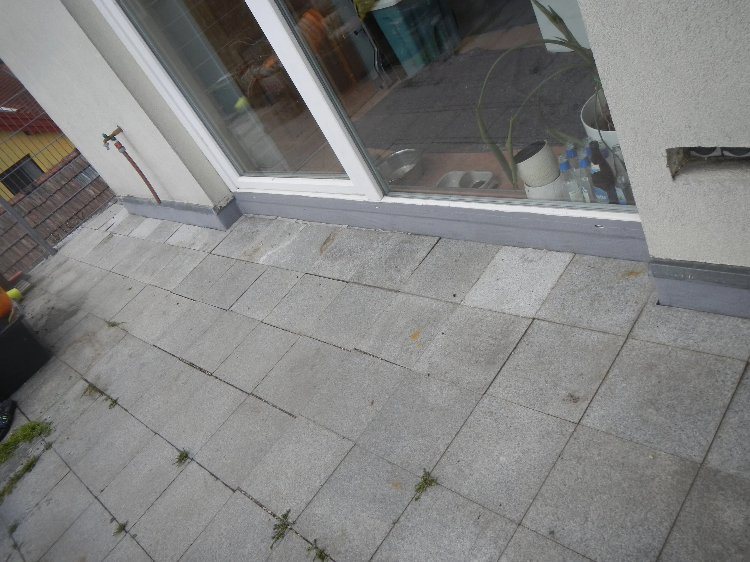 Ansicht einer Terrasse von schräg oben mit Waschbetonplatten und der Anschlusstelle zwischen Terrassentüre und Terrasse.