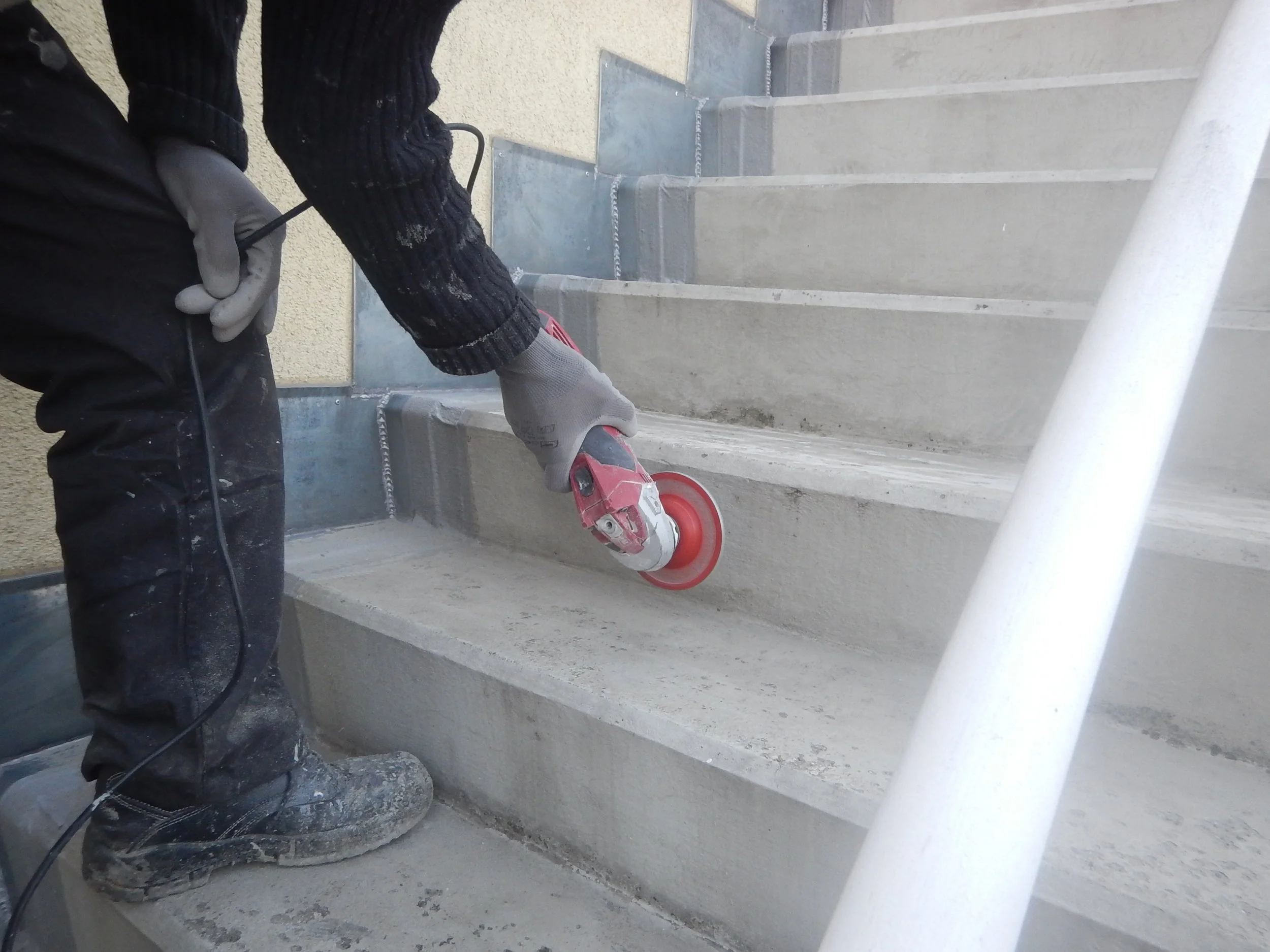 Arbeiter beim Anschleifen des Untergrundes zur fachbereiten Vorbereitung der weiteren Verarbeitung