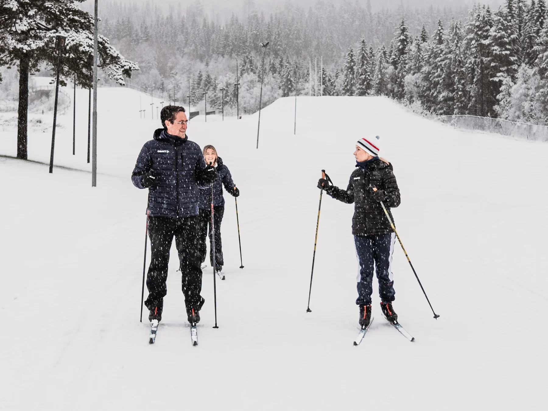 A female crosscountry skiing instructor teaches a couple how to cross country ski in birkebeineren skistadion in Lillehammer