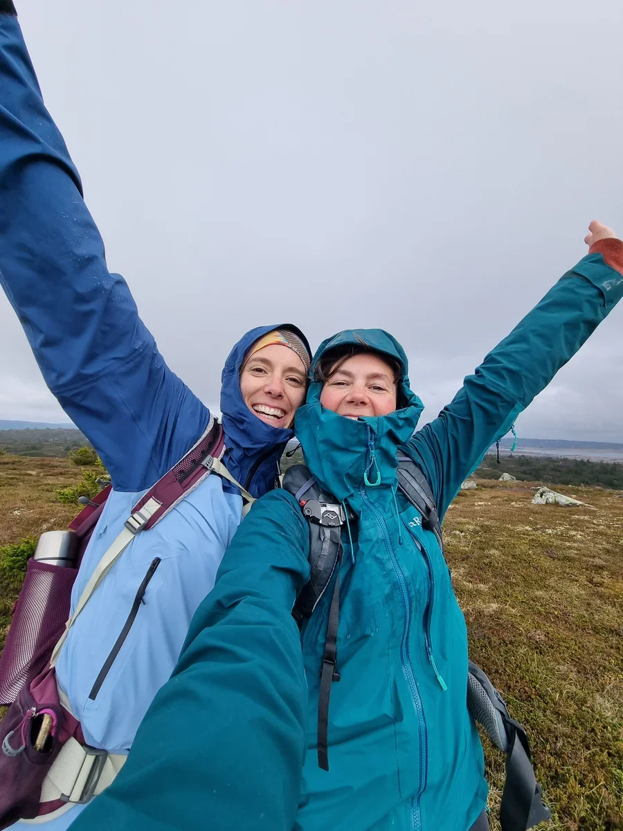 Two smiling women in rain jackets taking a selfie outdoors