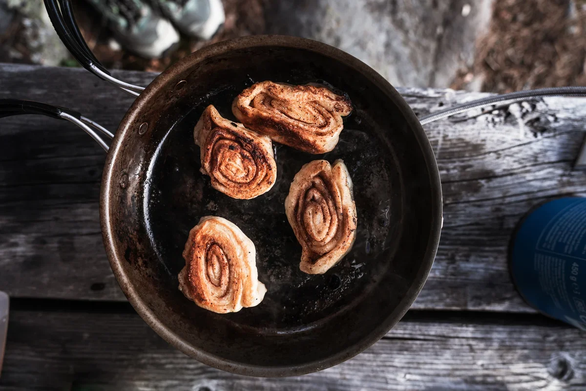 A top down shot of cinnamon rolls in a pan on top of a wooden table