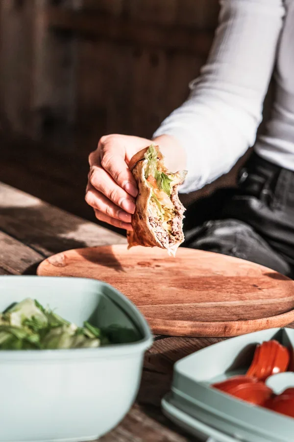 A photo of a hand holding a half eaten burger wrap
