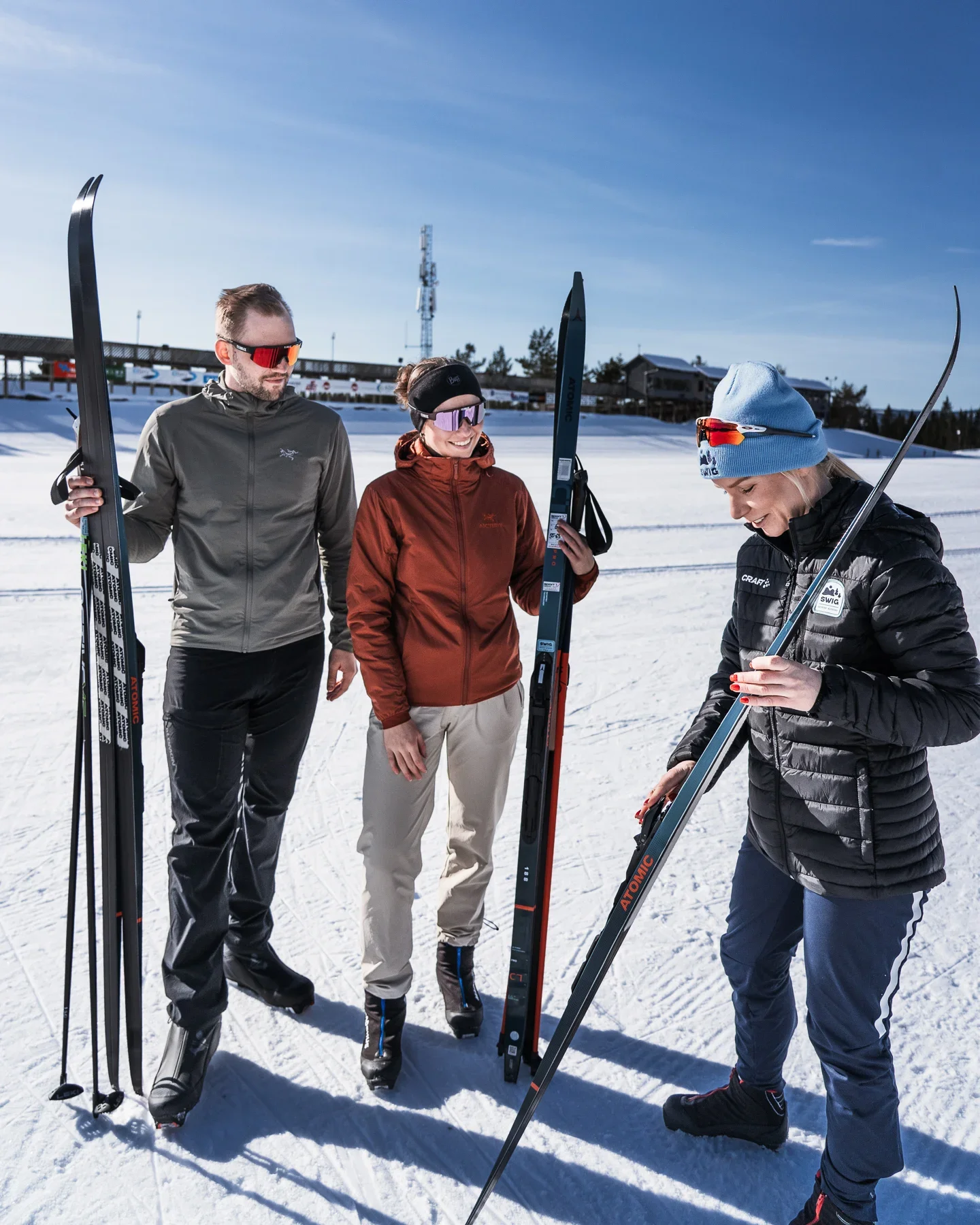 A couple with skls in their hands looking at their skiing teacher who explains the ski to them.