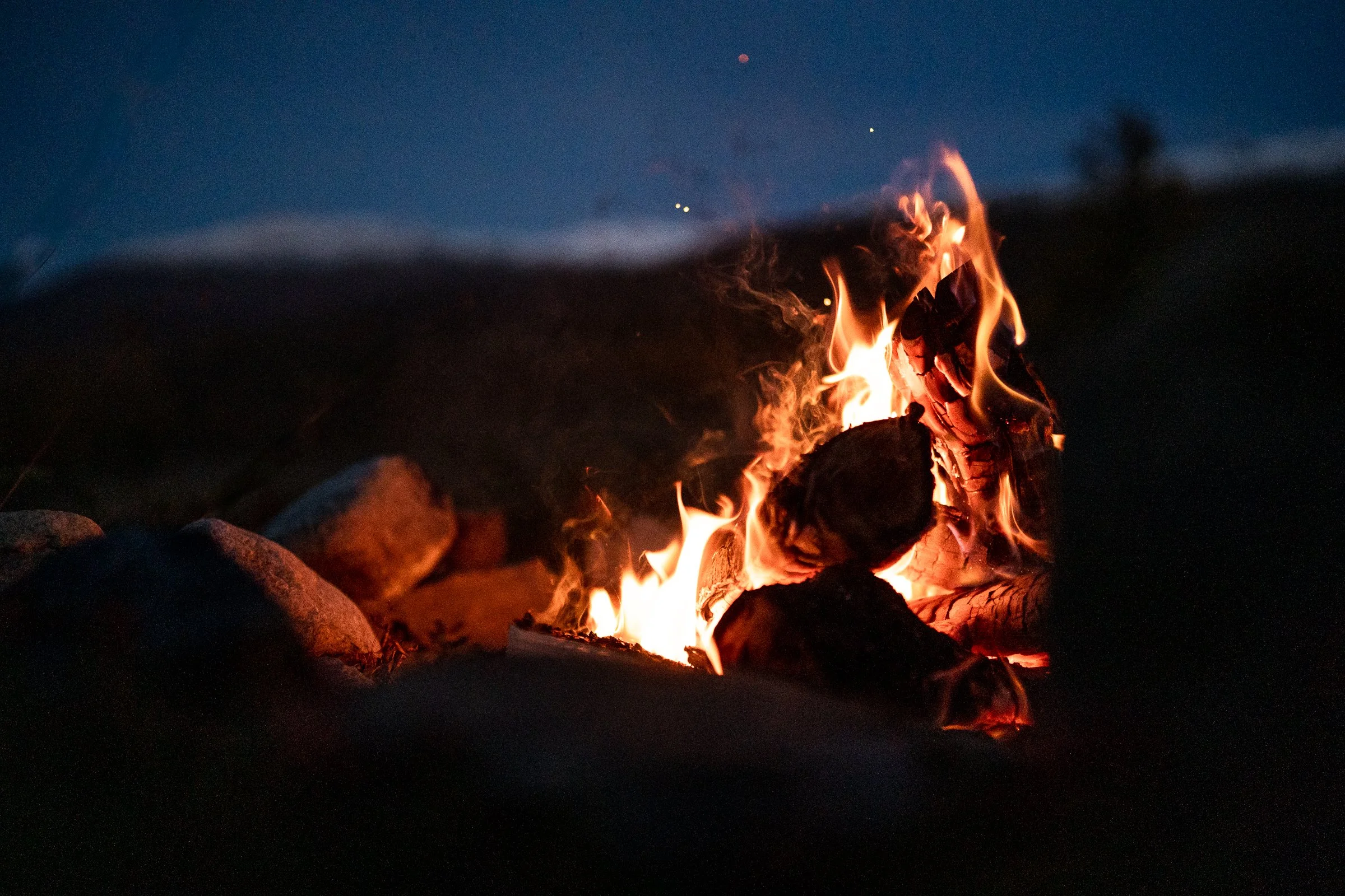 Guests making traditional Norwegian pinnebrød over a bonfire during a guided hike near Lillehammer