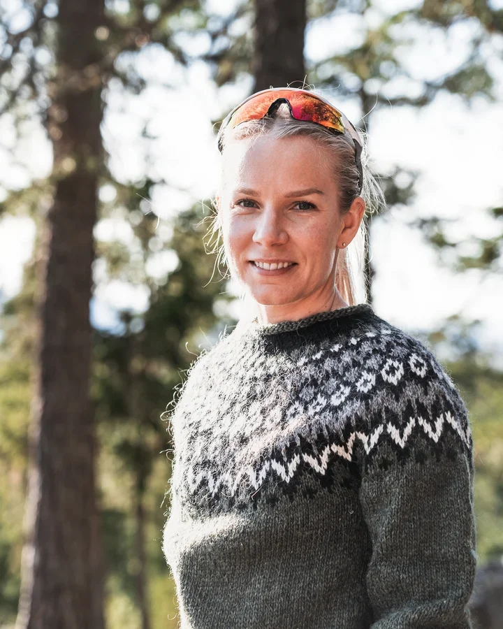 A photo of a blonde woman in a woolen sweater smiling into the camera.