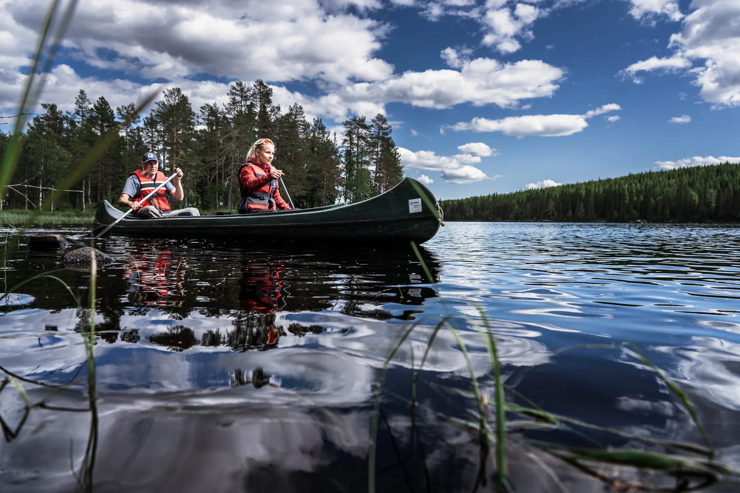A woman and a man paddling in a canoe on a lake.