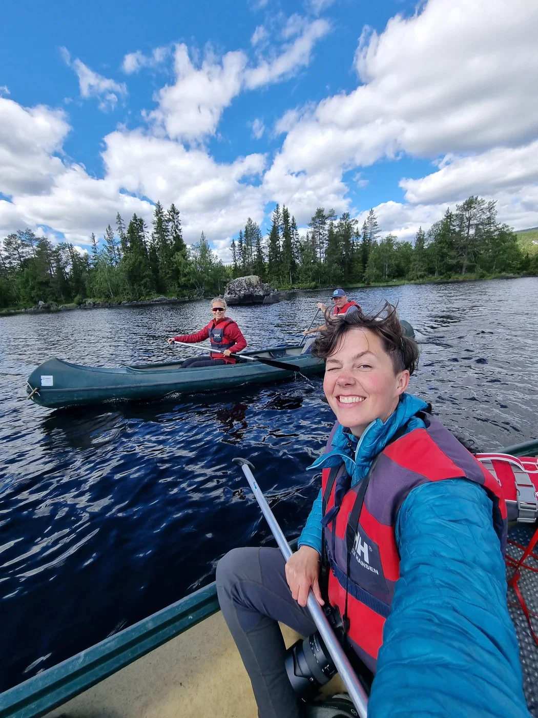  A selfie of a woman in a canoe. In the background a second canoe with 2 people is visible