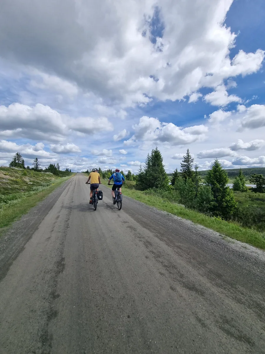 Two cyclists cycling next to each other along a gravel road
