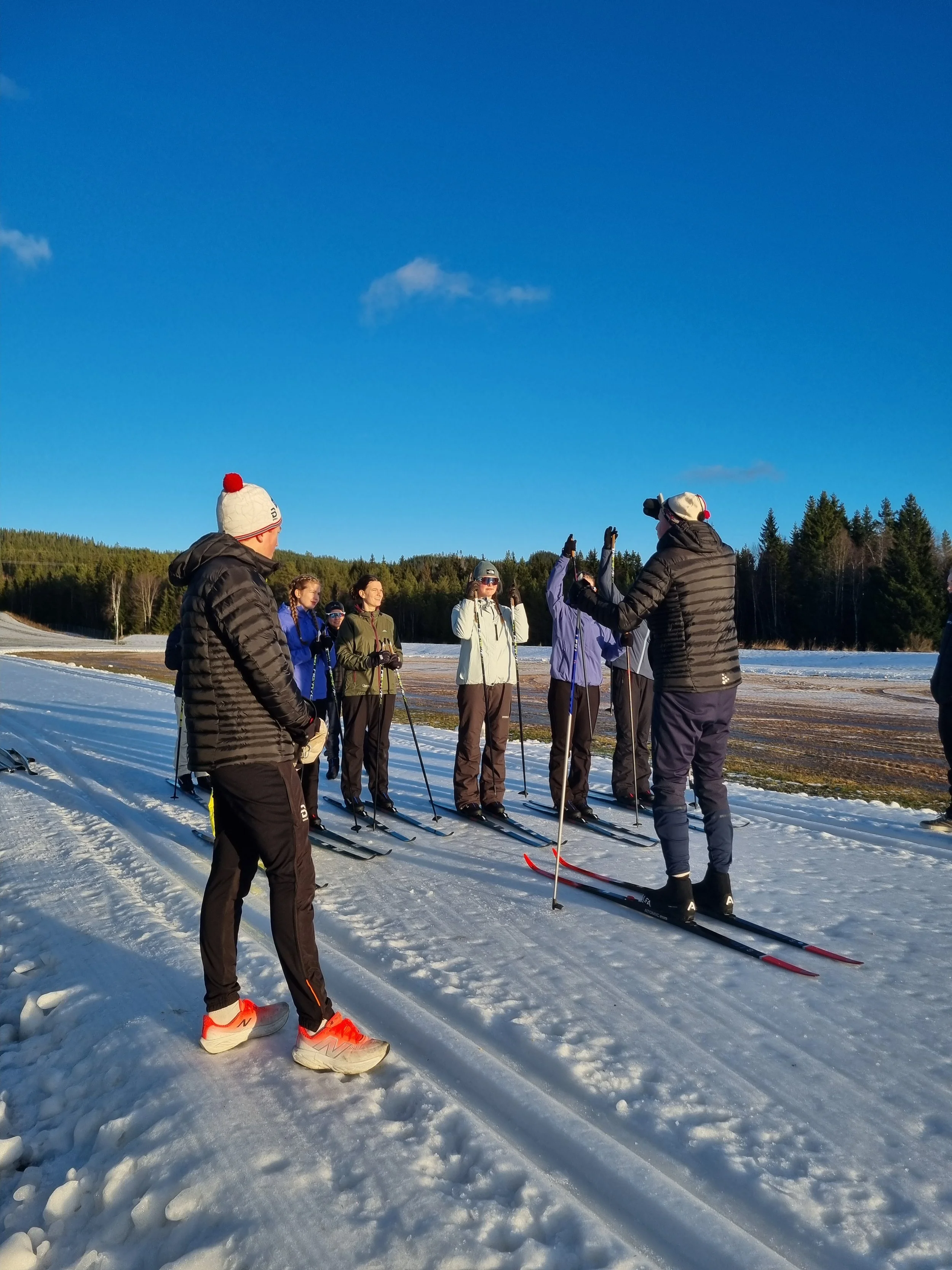 a group of people standing on a cross-country skiing track, the guide explains while the group listens
