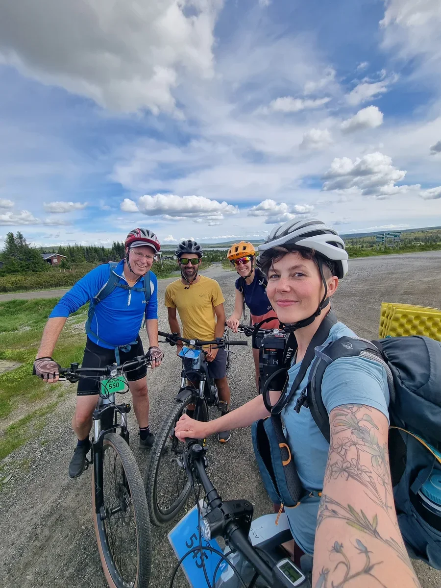 Four cyclists taking a selfie together, smiling into the camera while sitting on their bikes