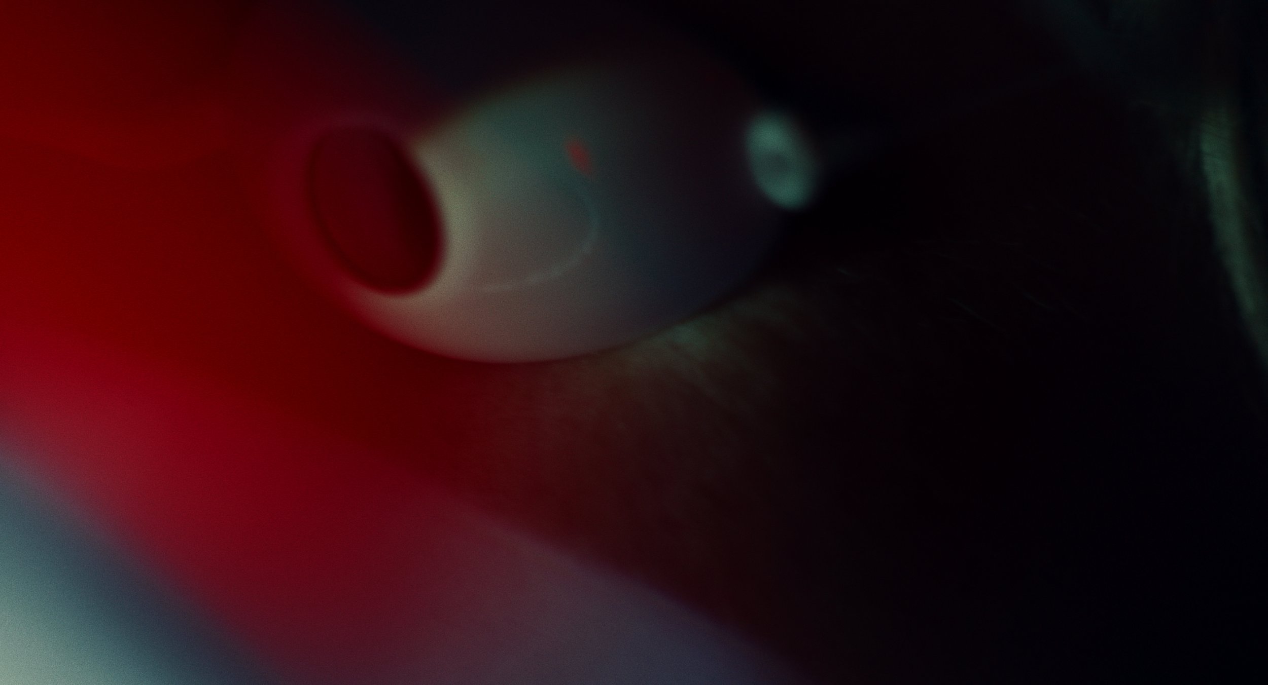 Close-up of electronic device with a circular button and small display, set against a dark background with red and green lighting.