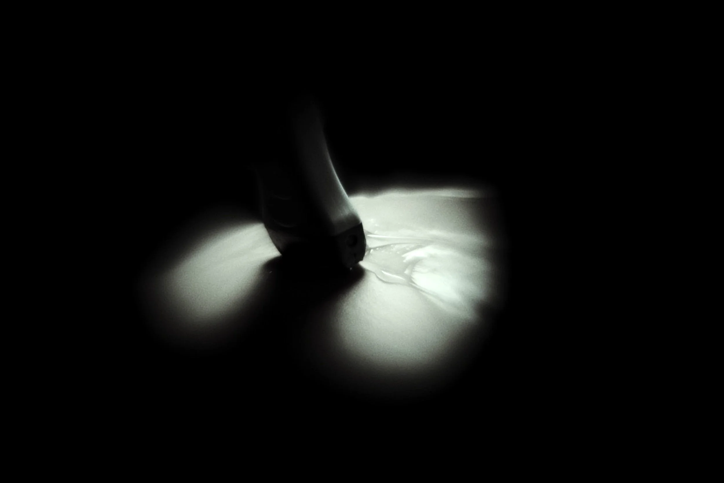 Close-up of a fountain pen writing on paper, illuminated in a dark environment.