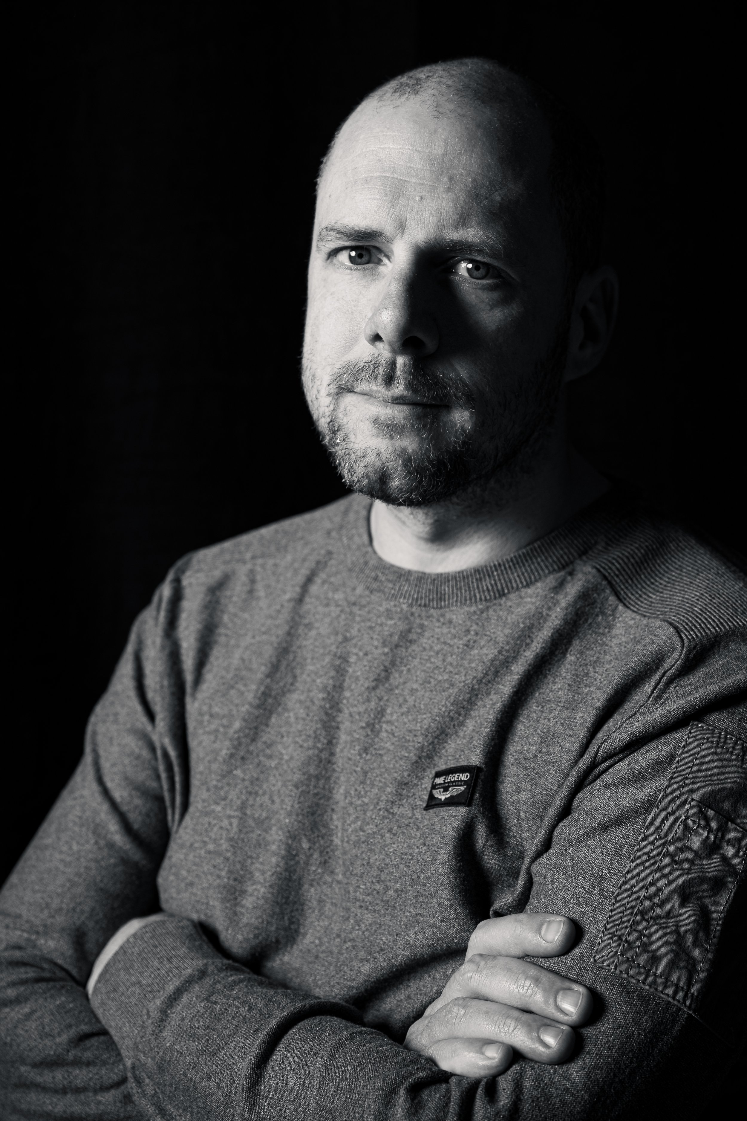 Zwart-wit zakelijk portret van ondernemer met armen over elkaar, zelfverzekerde en rustige uitstraling, studio Obdam