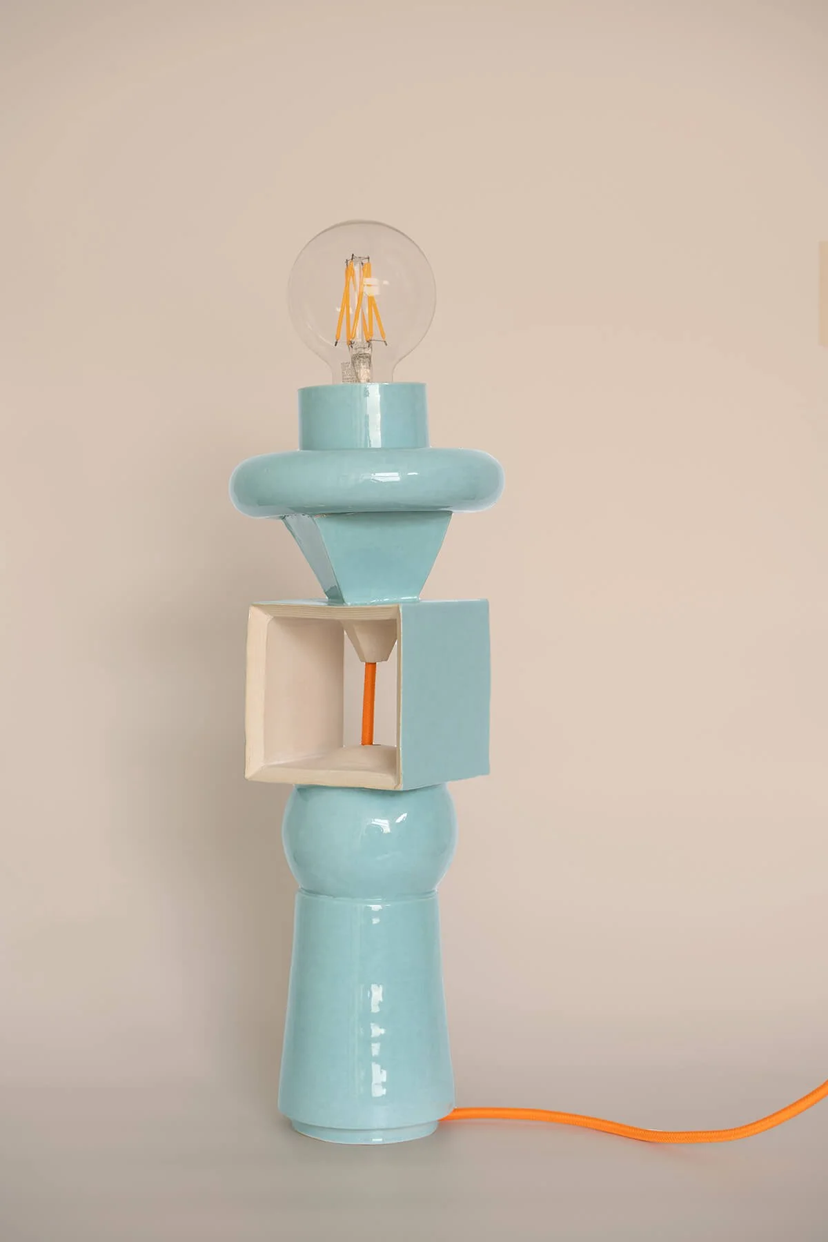 Handgemaakte aardewerk lamp in turquoise glazuur met sculpturale Memphis-vormen en een oranje snoer, ontworpen en vervaardigd door Linda Loef (LAB L.L.) in Vlaardingen.