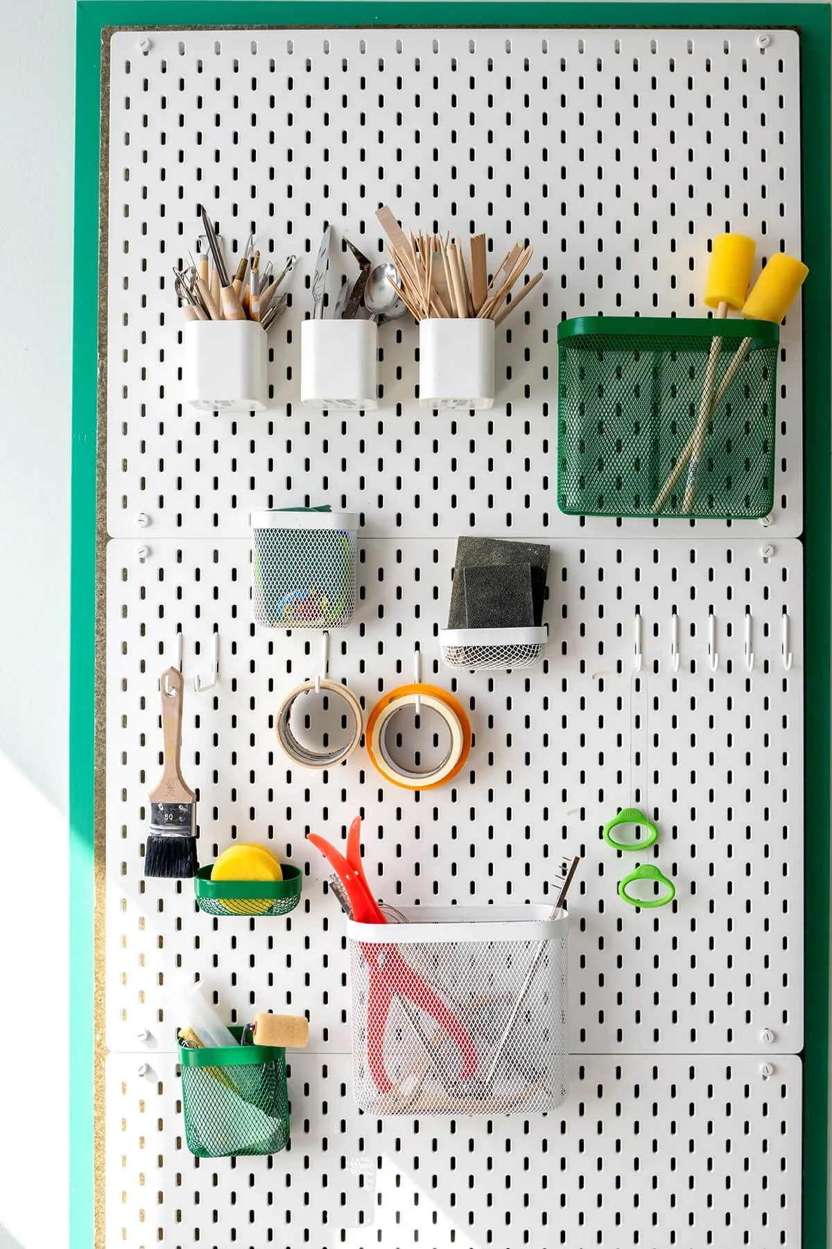 Gereedschapswand in het keramiekatelier van LAB L.L. met penselen, spatels, tape, scharen en andere tools overzichtelijk georganiseerd.