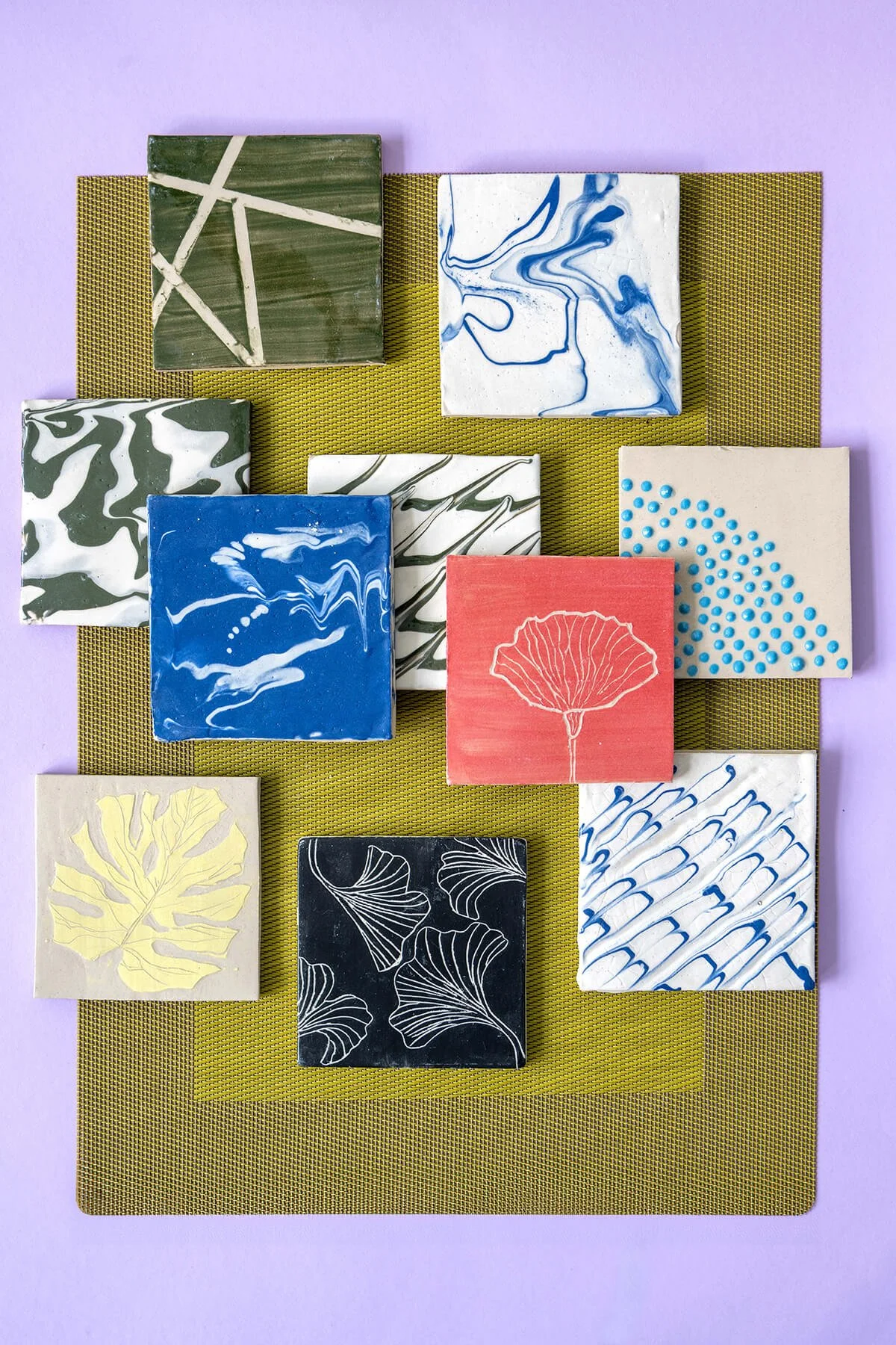 Flatlay van een kleurrijke collectie handgemaakte keramiektegels met diverse engobe decoratietechnieken, ontworpen door LAB L.L.