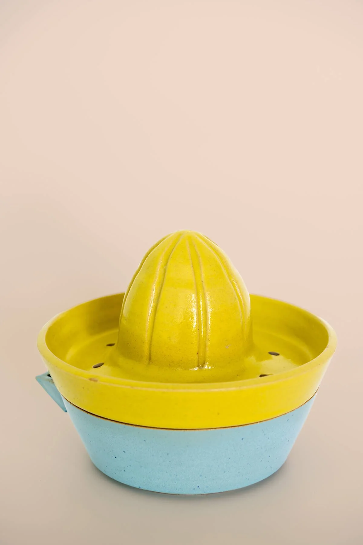 Handgemaakte steengoed citruspers in citroengeel en lichtblauw, bestaande uit een pers en opvangkom, gemaakt door Linda Loef (LAB L.L.) in Vlaardingen.