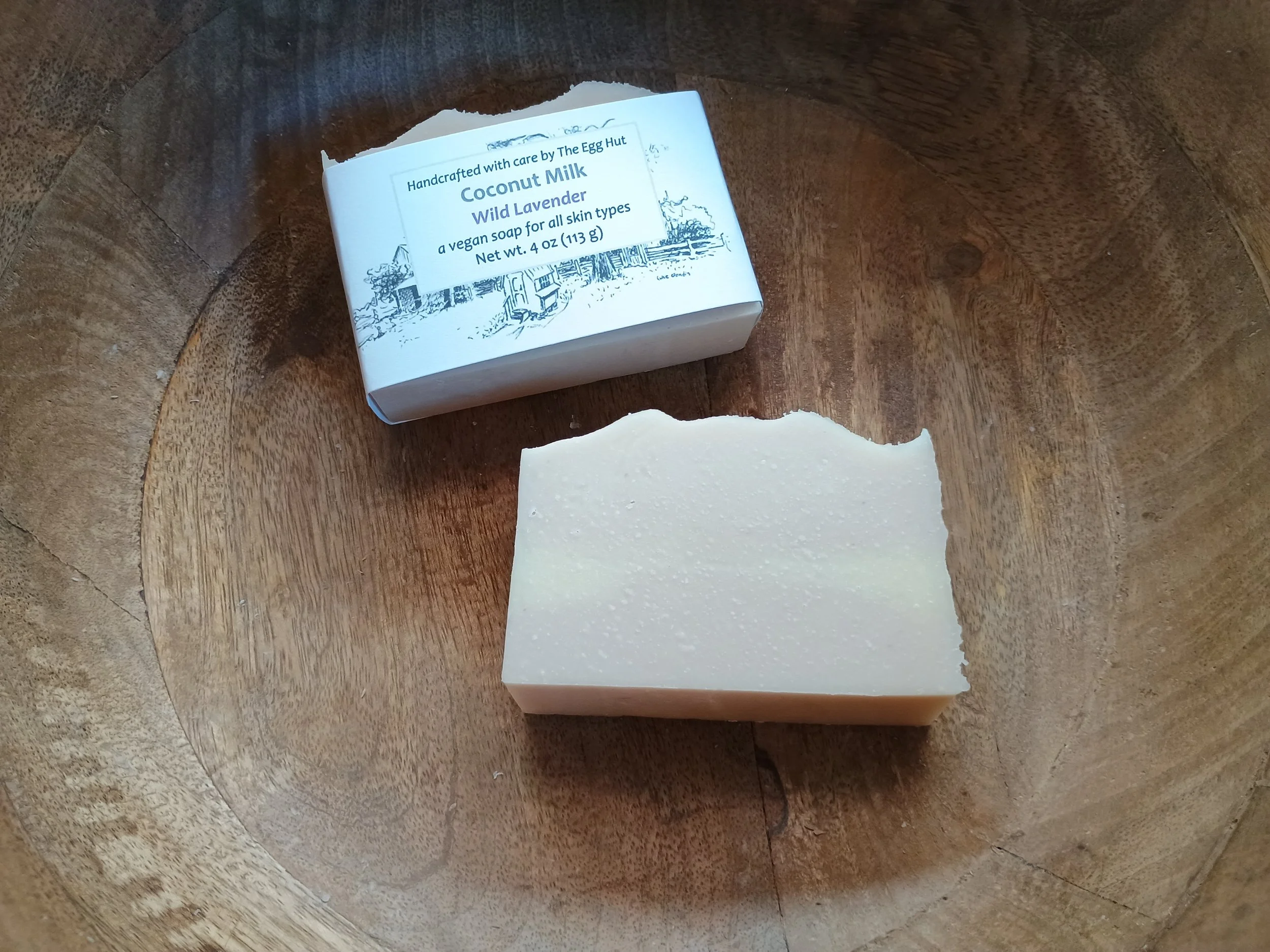 a wooden bowl with a soap bar with and without packaging