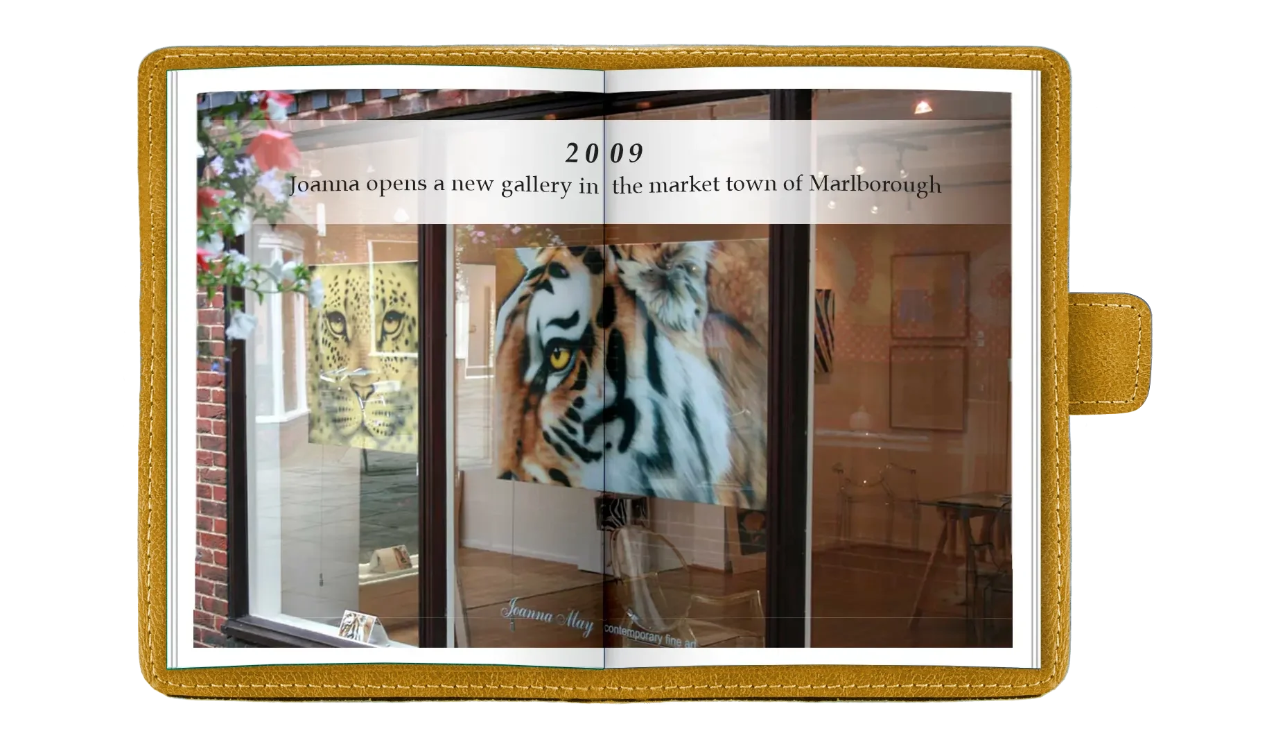 Open photo album showing an art gallery window with tiger artwork, a cheetah artwork, and a mural, with a caption about Joanna opening a new gallery in Marlborough in 2009.