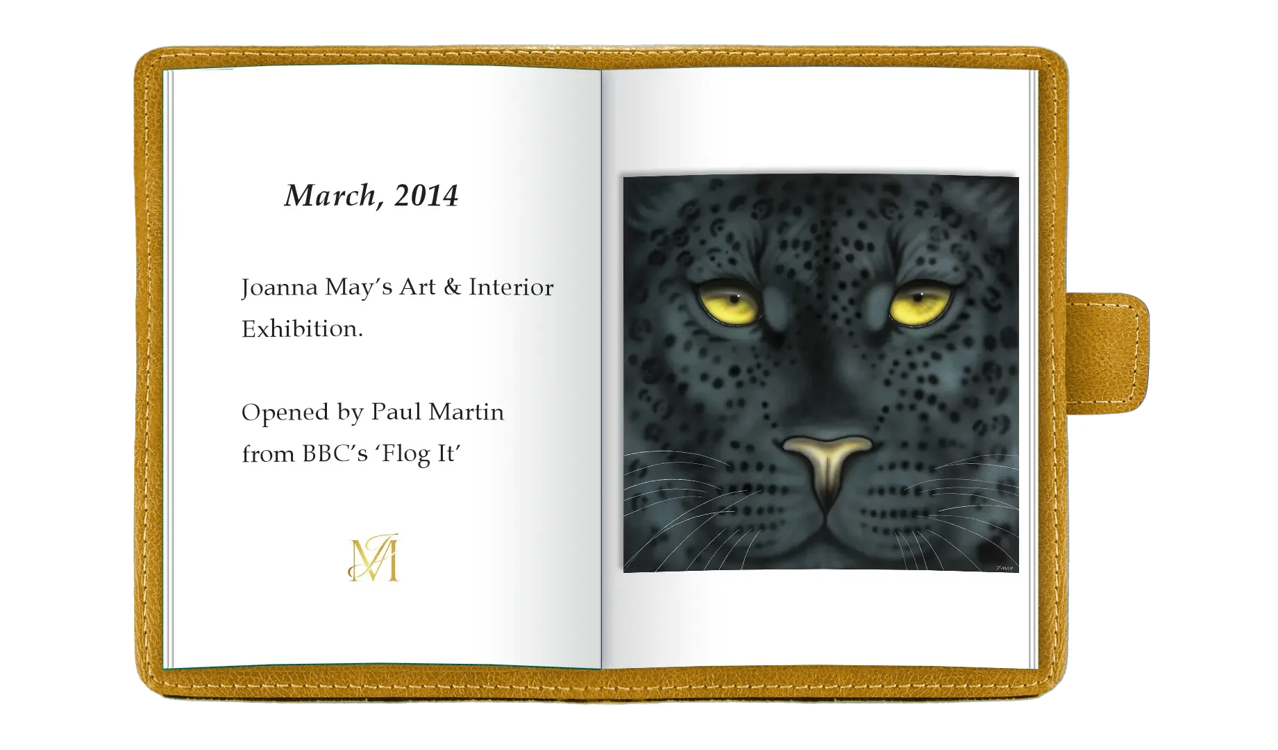 Open scrapbook with a gold edge cover, showing a page with black serif text on the left stating "March, 2014," "Joanna May’s Art & Interior Exhibition," and "Opened by Paul Martin from BBC’s ‘Flog It’"; an intricate gold monogram at the bottom left. 